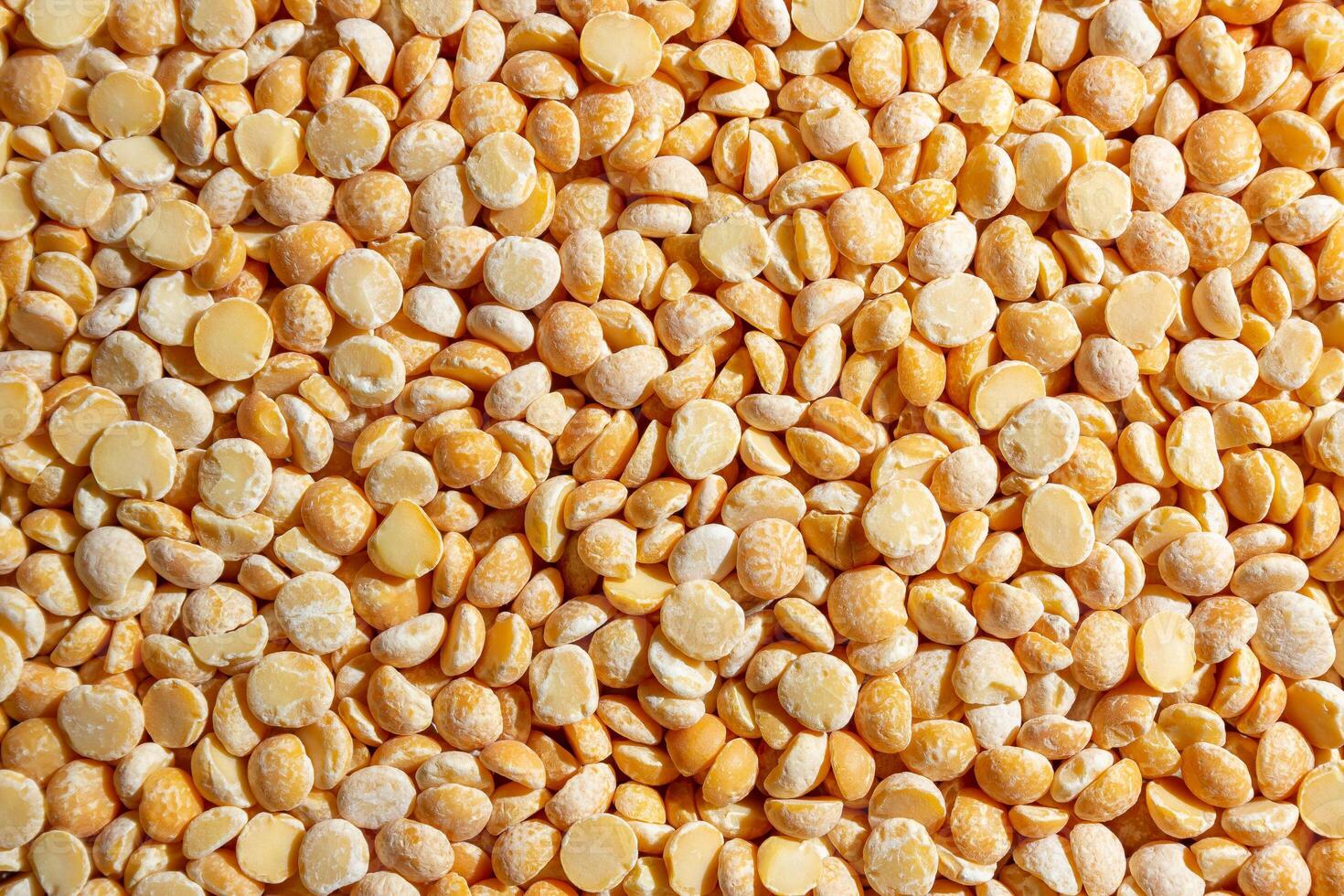 Uncooked Polished Split Peas Background. A Culinary Canvas of Dry Yellow Peas, Creating a Lively and Textured Background for Gourmet Cooking. Scattered Raw Polished Peas. Healthy Eating Ingredients photo
