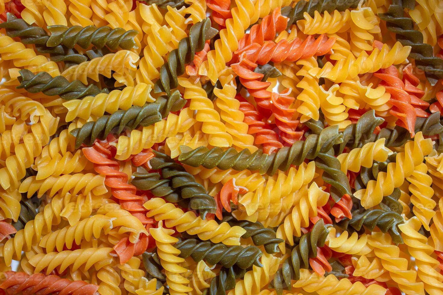 Uncooked Vibrant Colored Fusilli Pasta. A Mesmerizing Culinary Canvas of Multicolored Spirals, Creating a Lively and Textured Background for Gourmet Cooking. Colored Dry Pasta. Raw Macaroni photo