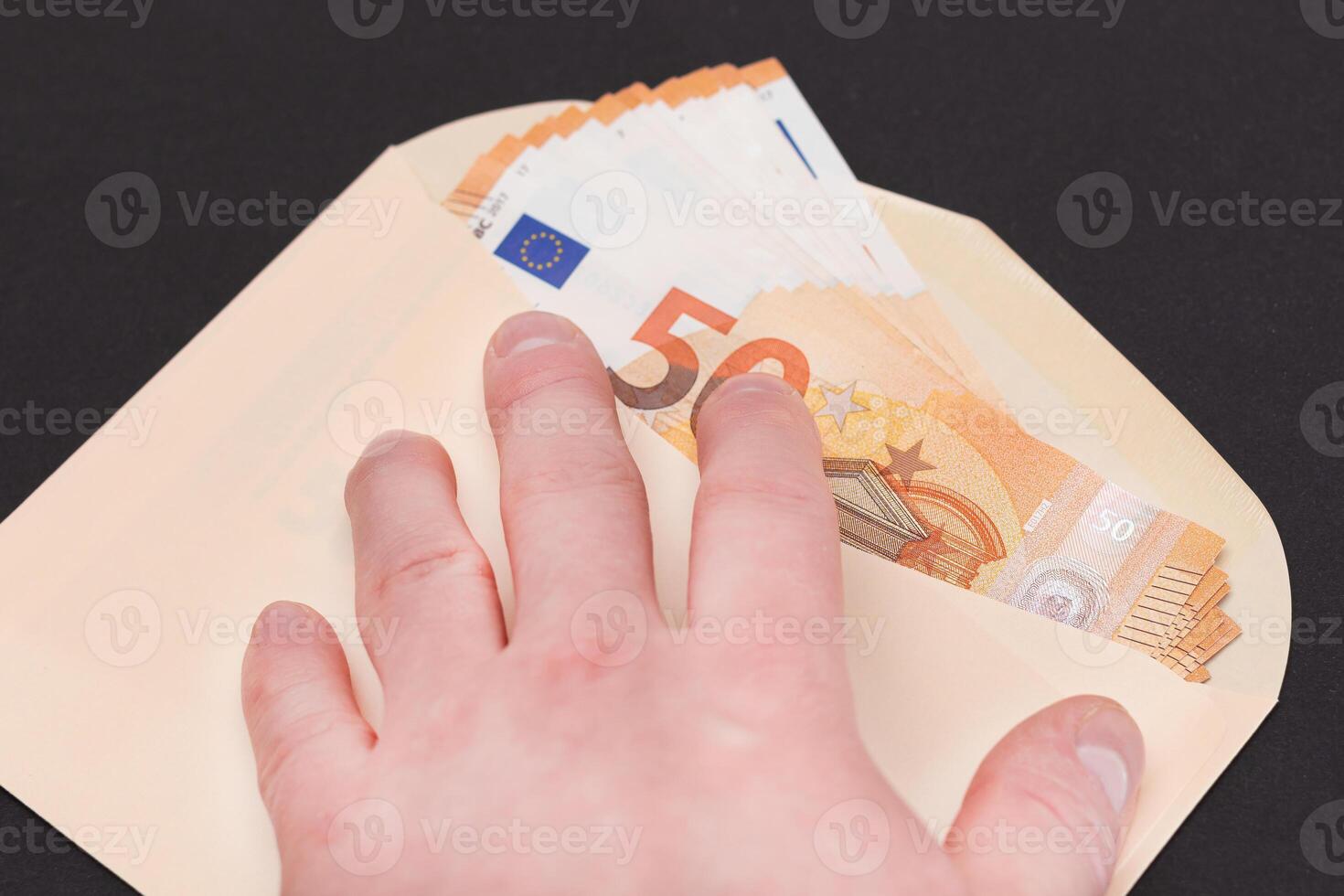 Hand Holds An Orange Paper Envelope with Stack of 50-Euro Banknotes Inside. Salary in Cash. Tax-Free System. Euro Currency. Payments with No Taxes. Orange Paper Money. A Lot of Fifty-Euro Bills photo