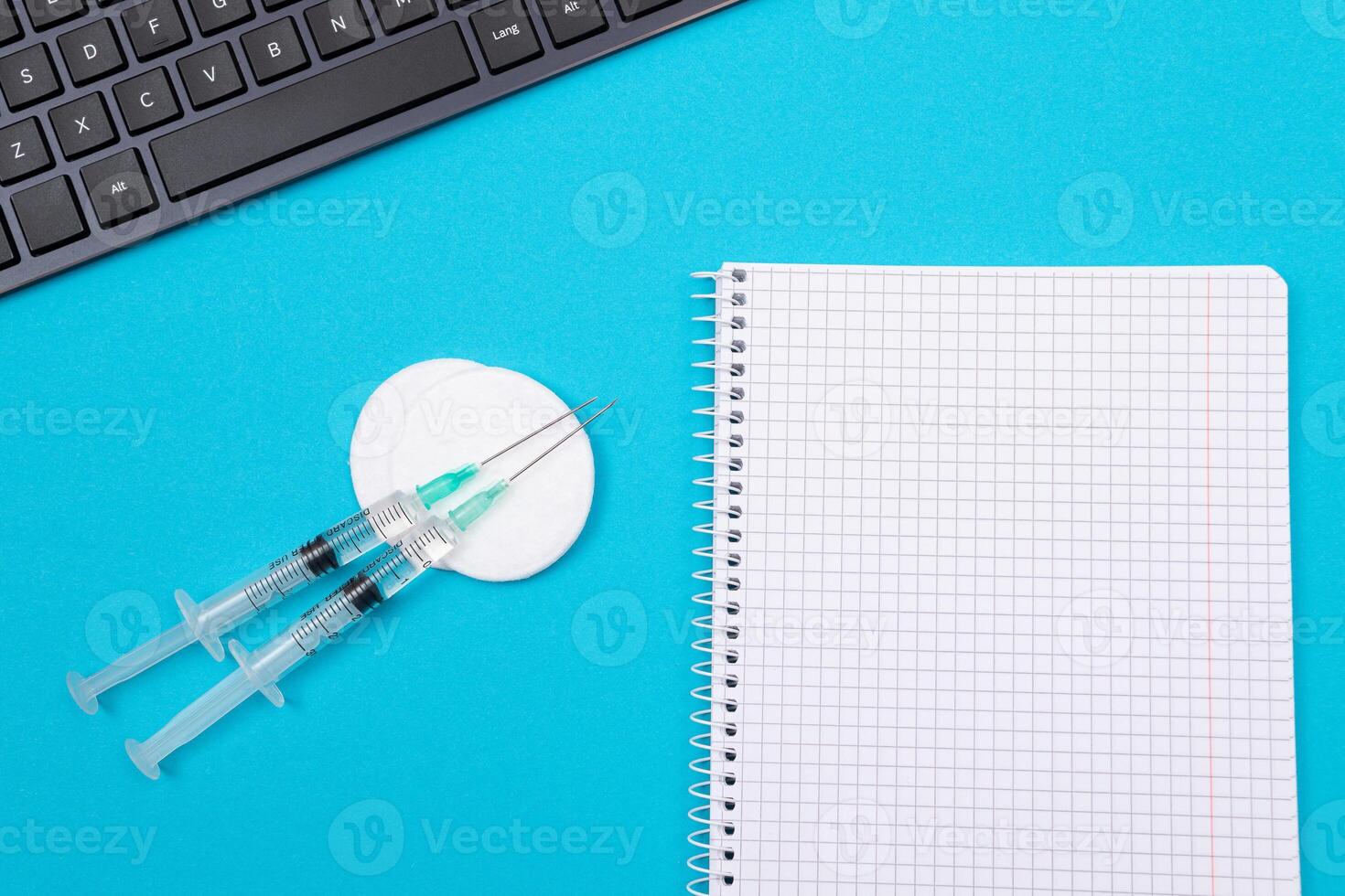 Vaccination, Immunology or Revaccination Concept - Two Medical Syringe Lying on Blue Table in Doctor's Office in a Hospital or Clinic. Opened Blank Notepad - Mock Up with Copy Space photo