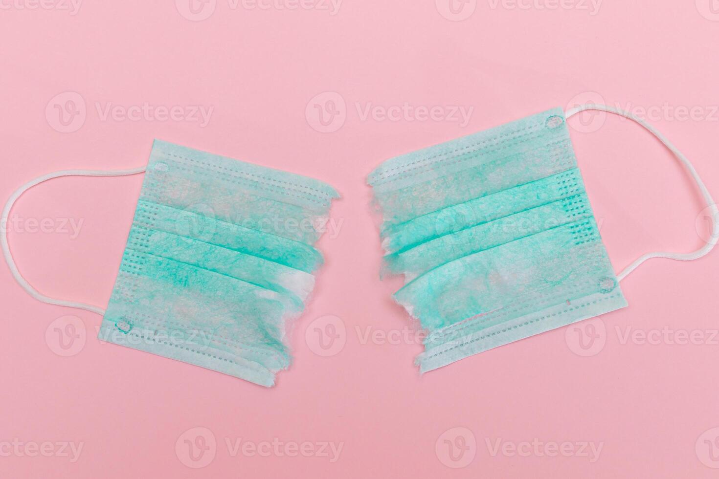 Anti Mask Movement - Green Torn Medical Face Mask on the Pink Background. Pandemic and Lockdown End - Top View, Flat Lay photo