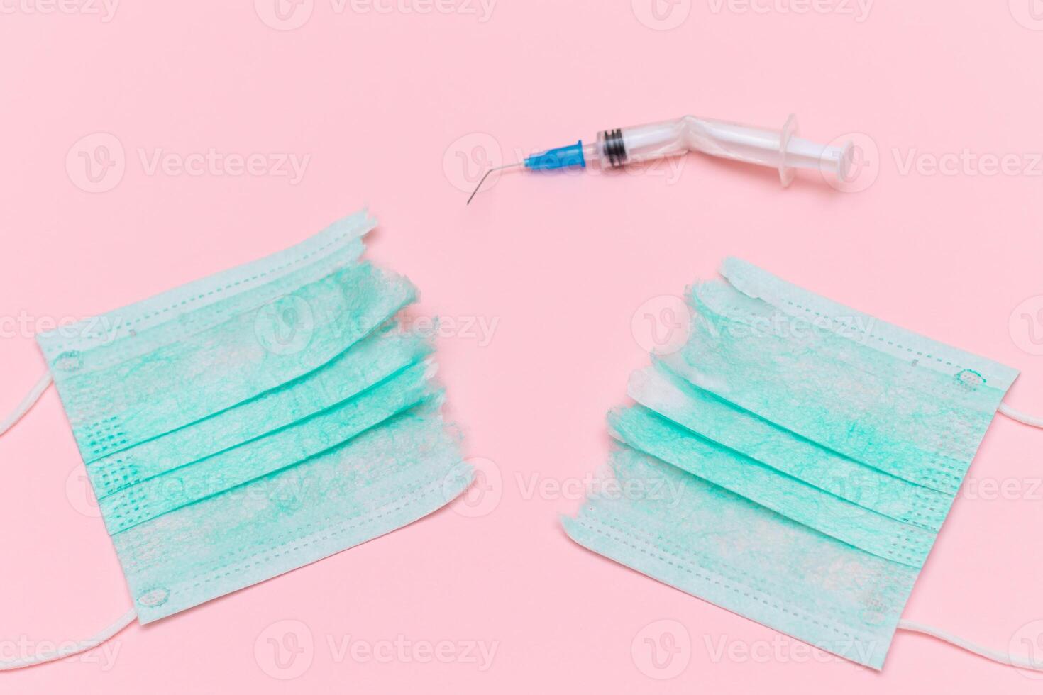 Anti Vaccine Movement and Anti Mask Concept - Broken Medical Syringe and Green Torn Medical Face Mask on the Pink Background. Pandemic and Lockdown End - Top View, Flat Lay photo
