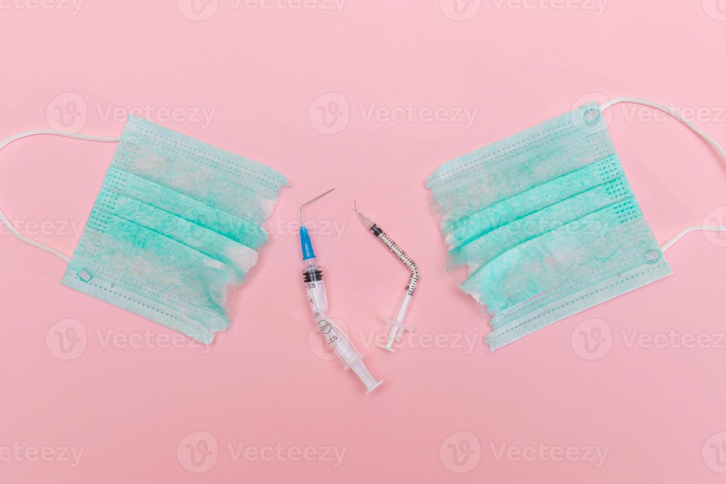 Anti Vaccine Movement and Anti Mask Concept - Broken Medical Syringe and Green Torn Medical Face Mask on the Pink Background. Pandemic and Lockdown End - Top View, Flat Lay photo
