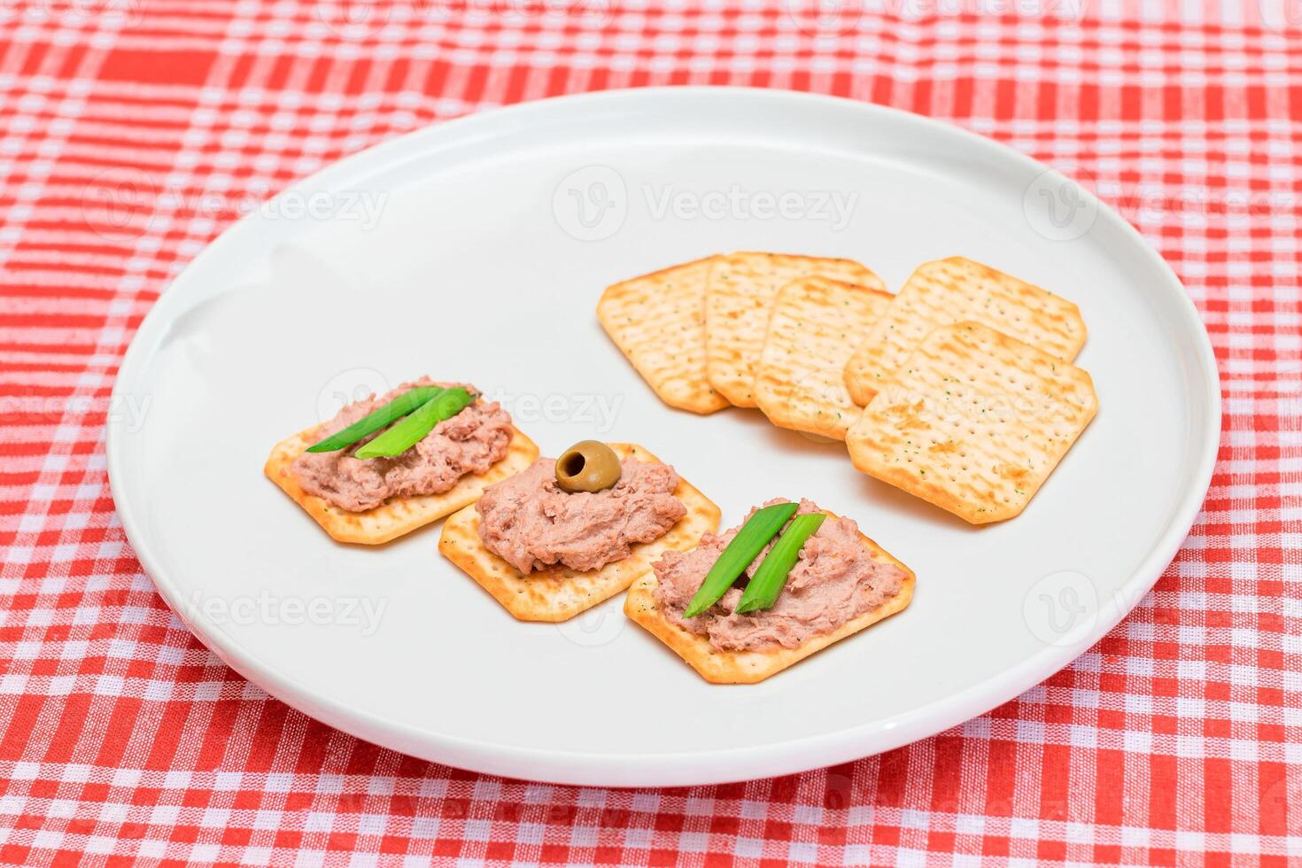 Crispy Salted Crackers with Liver Pate, Green Onions and Olives on White Plate. Easy Snack photo