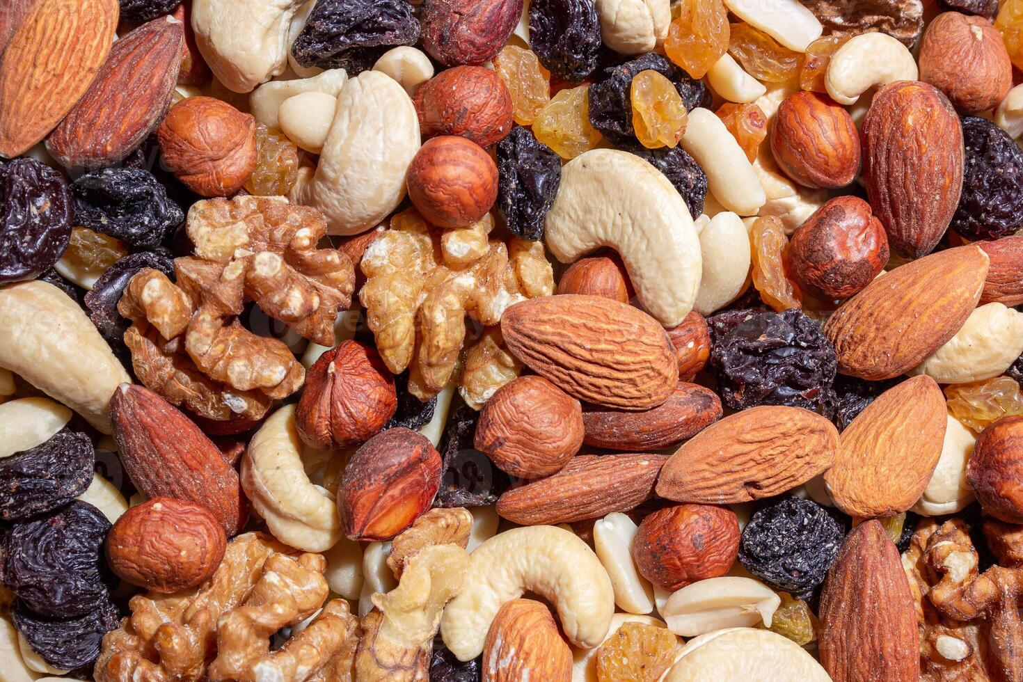 Mixed Nuts. Almonds, Walnuts, Cashews, Peanuts, Hazelnuts, Dried Prunes and Raisins. Different Nut Mix. Background from Various Nuts and Dried Fruits photo