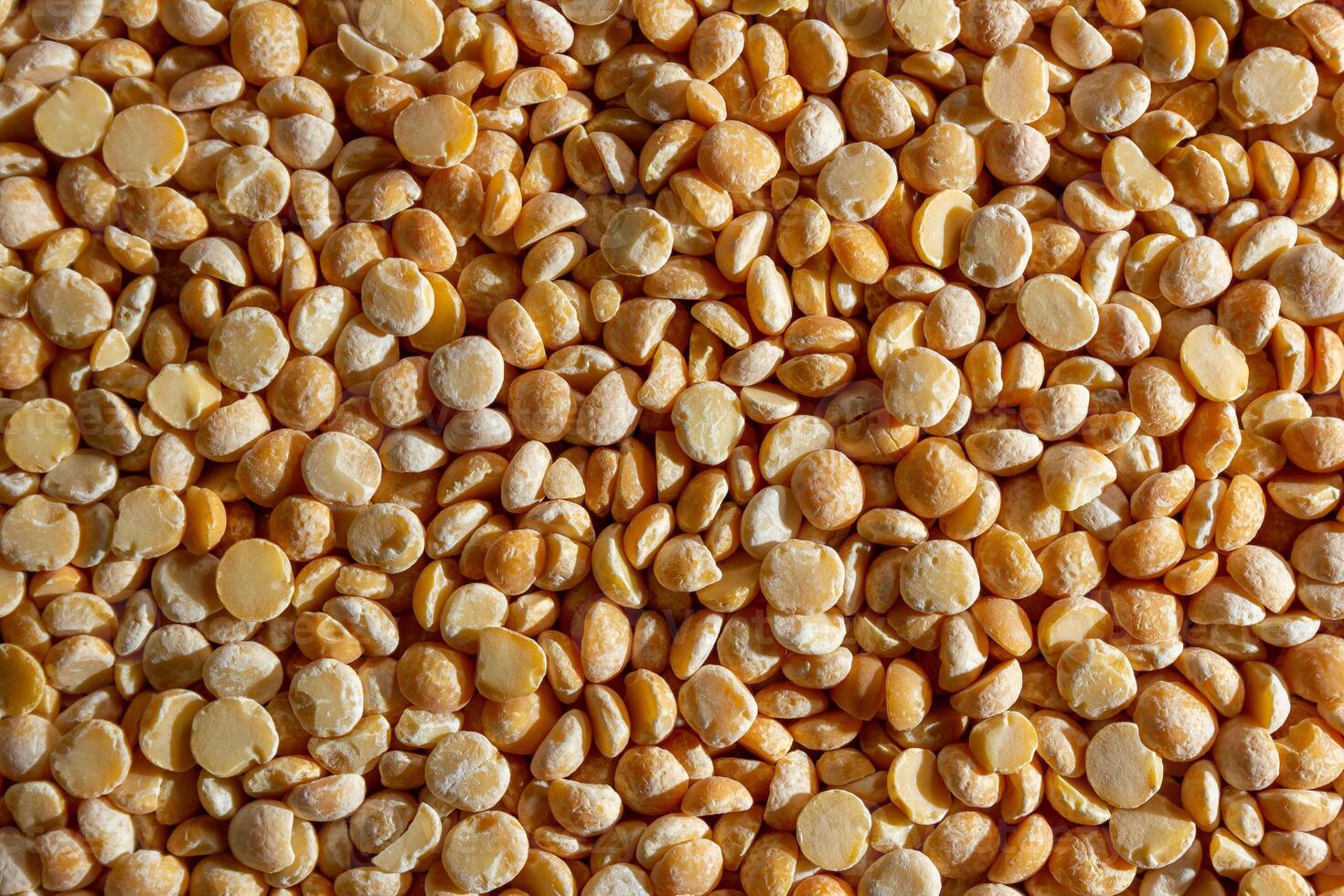 Uncooked Polished Split Peas Background. A Culinary Canvas of Dry Yellow Peas, Creating a Lively and Textured Background for Gourmet Cooking. Scattered Raw Polished Peas. Healthy Eating Ingredients photo