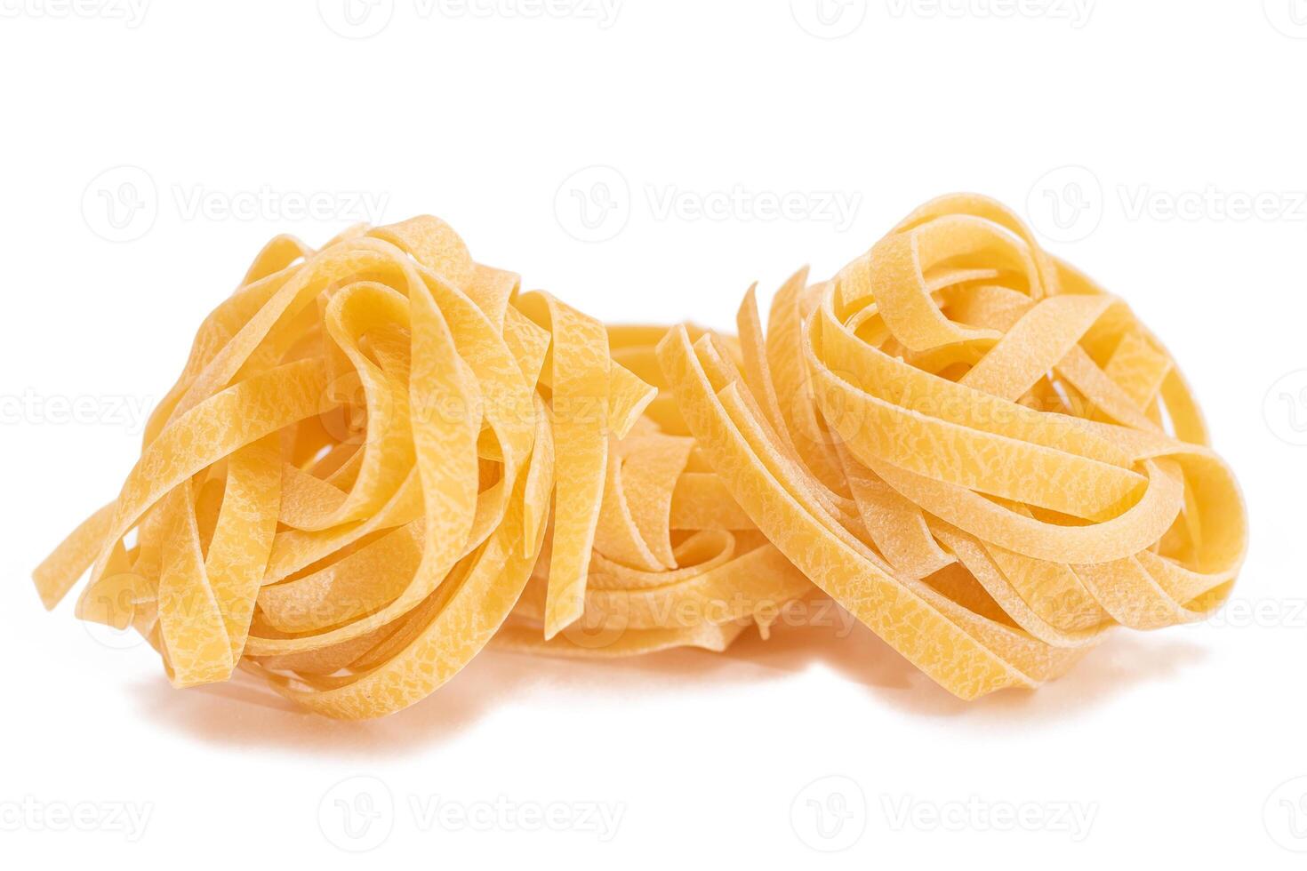 Three Classic Italian Raw Egg Fettuccine - Isolated on White Background. Dry Twisted Uncooked Pasta. Italian Culture and Cuisine. Raw Golden Macaroni Pattern - Isolation photo
