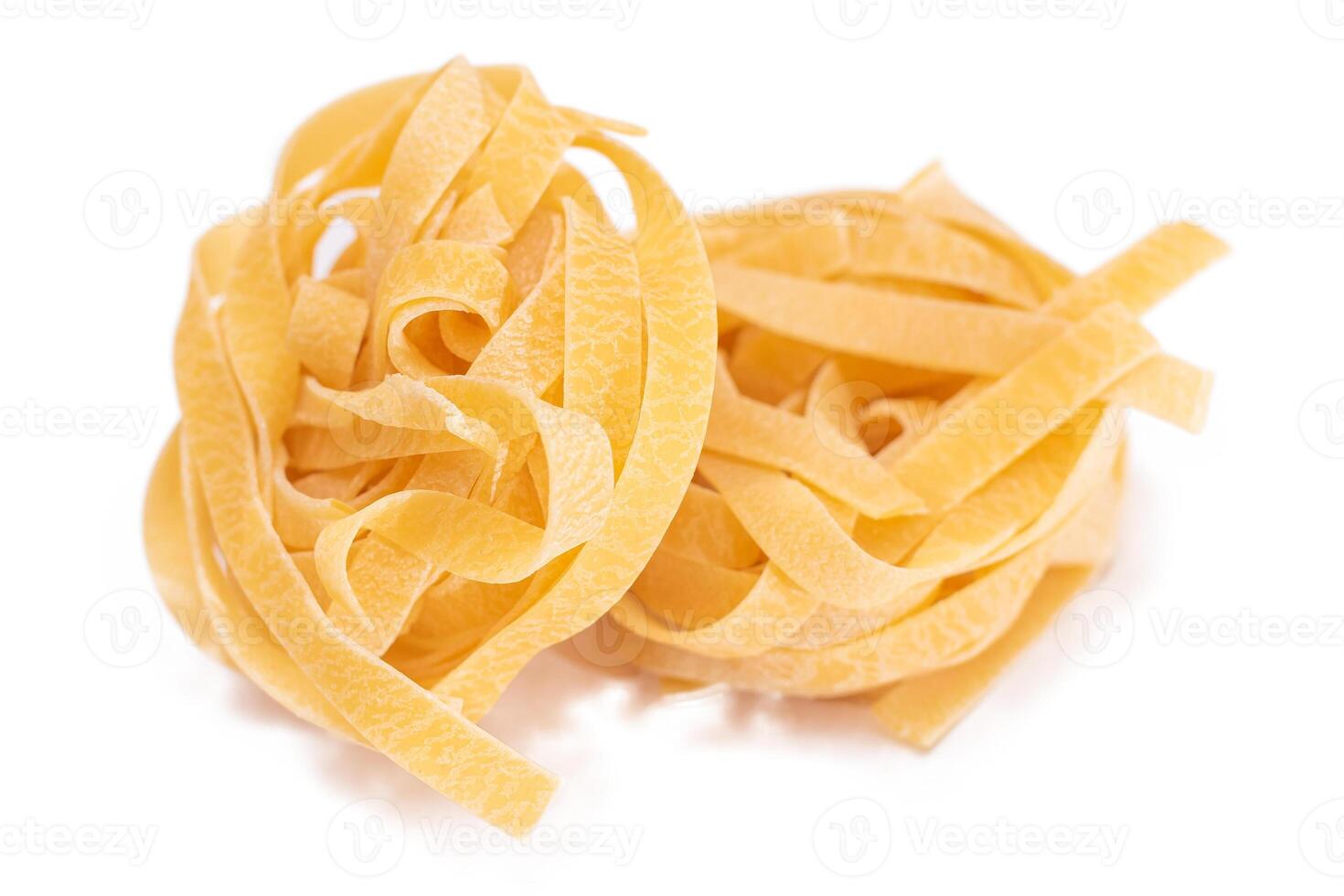 Two Classic Italian Raw Egg Fettuccine - Isolated on White Background. Dry Twisted Uncooked Pasta. Italian Culture and Cuisine. Raw Golden Macaroni Pattern - Isolation photo