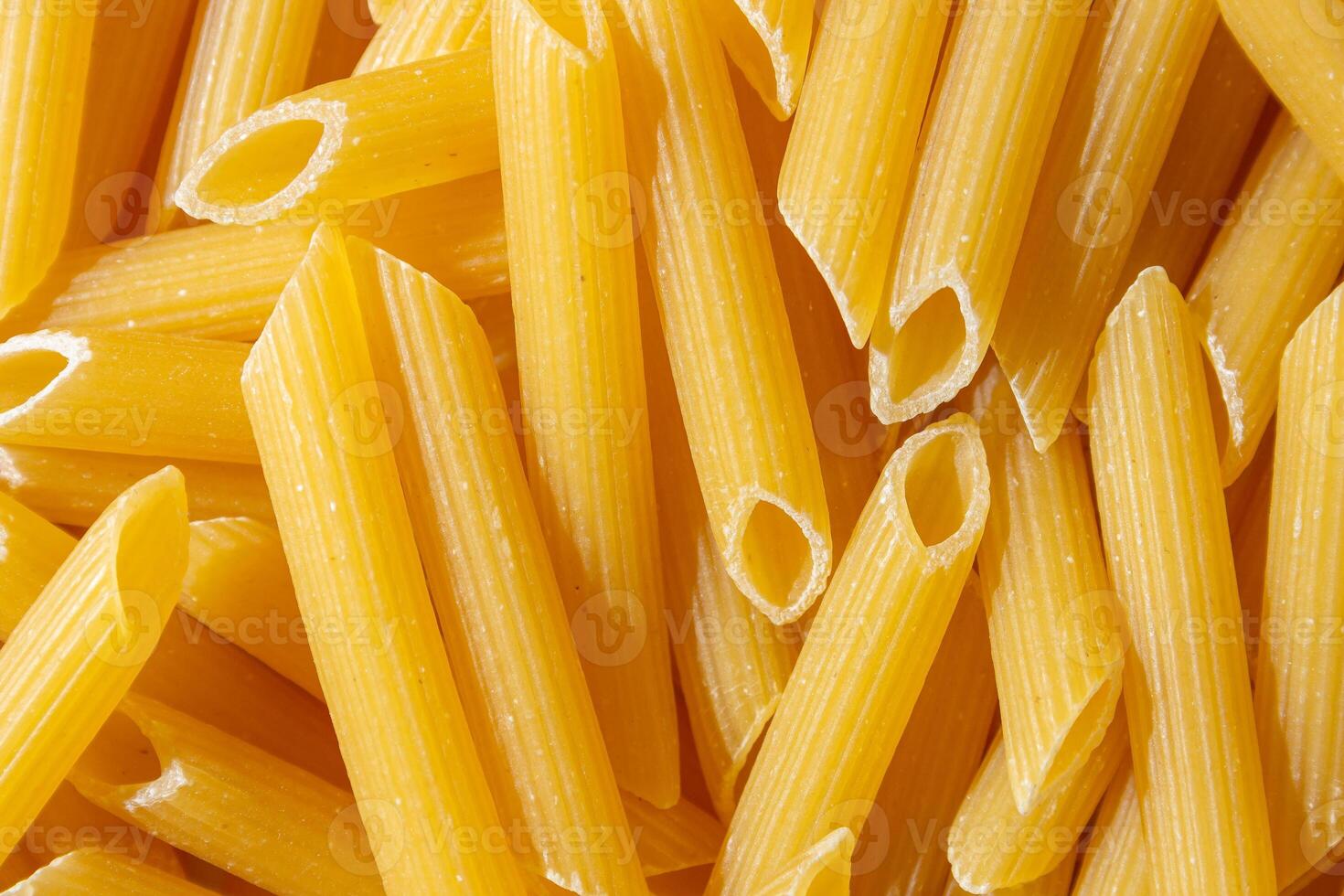 Uncooked Penne Rigate Pasta. A Culinary Canvas of Penne Macaroni, Creating a Lively and Textured Background for Gourmet Cooking. Dry Pasta. Raw Macaroni - Top View, Flat Lay photo