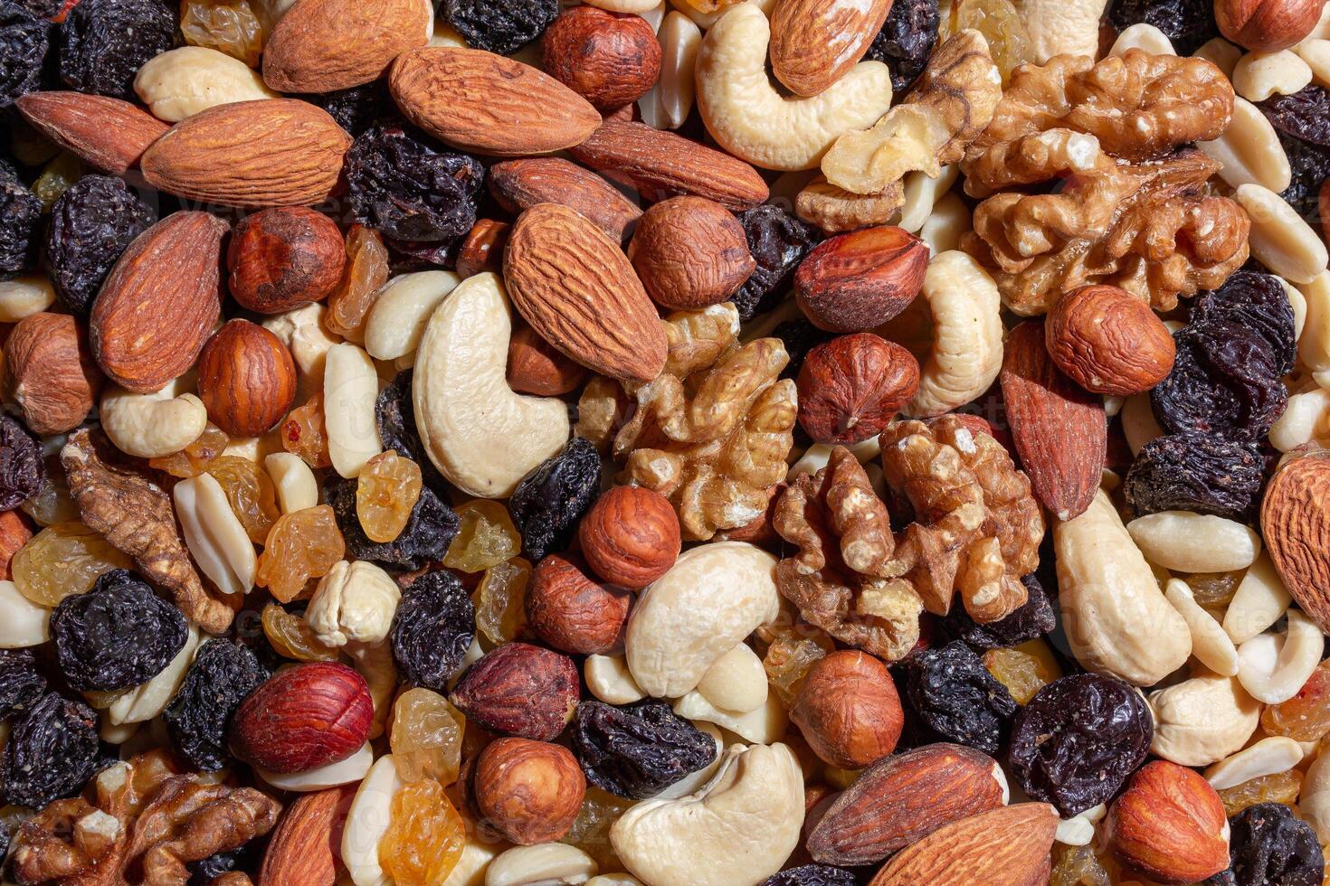 Mixed Nuts. Almonds, Walnuts, Cashews, Peanuts, Hazelnuts, Dried Prunes and Raisins. Different Nut Mix. Background from Various Nuts and Dried Fruits photo