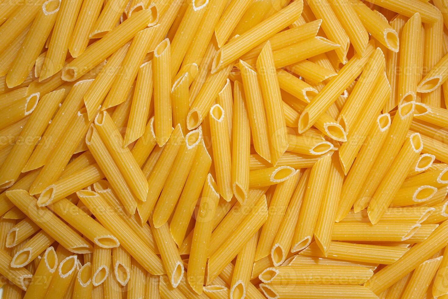 Uncooked Penne Rigate Pasta. A Culinary Canvas of Penne Macaroni, Creating a Lively and Textured Background for Gourmet Cooking. Dry Pasta. Raw Macaroni - Top View, Flat Lay photo