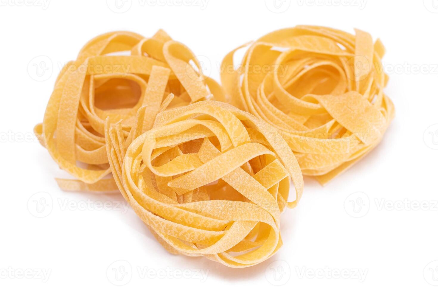 Three Classic Italian Raw Egg Fettuccine - Isolated on White Background. Dry Twisted Uncooked Pasta. Italian Culture and Cuisine. Raw Golden Macaroni Pattern - Isolation photo