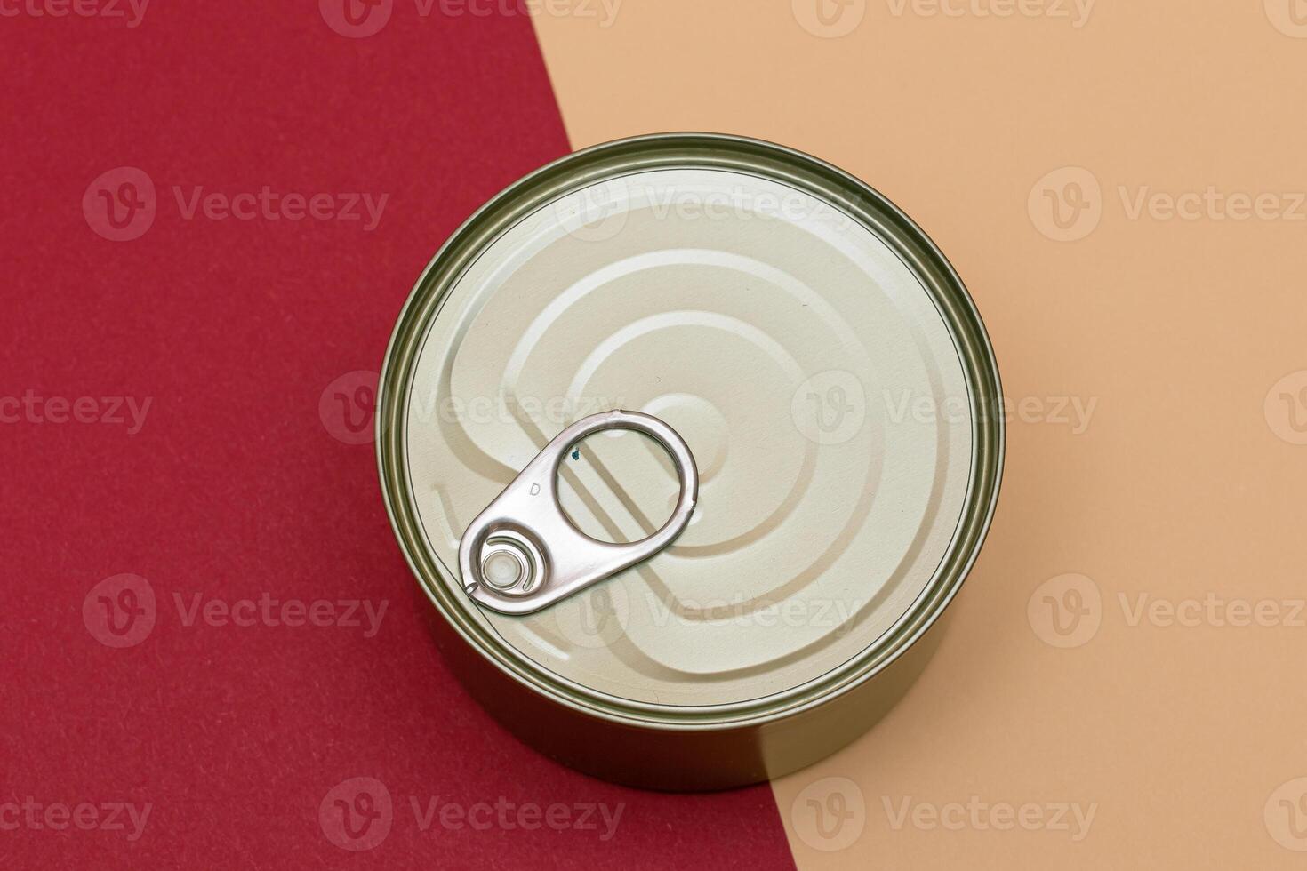 Unopened Tin Can with Blank Edge on Split Red and Beige Background. Canned Food. Aluminum Can for Safe and Long Term Storage of Food. Steel Sealed Food Storage Container photo