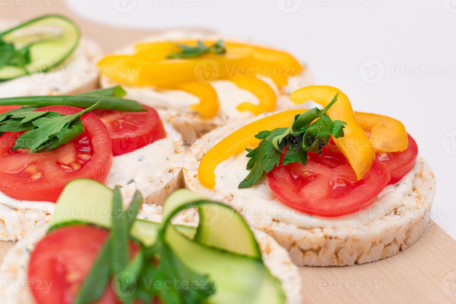 Different Vegan Rice Cake Sandwiches with Fresh Tomato, Yellow Paprika and Greens on Wooden Cutting Board. Vegetarian Diet Food. Quick and Healthy Sandwiches. Crispbread with Fresh Fillings photo