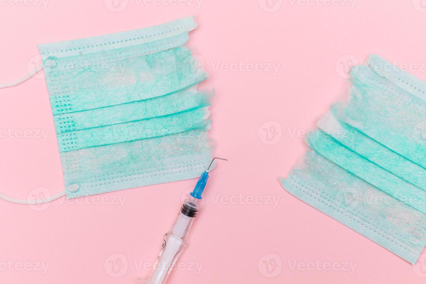 Anti Vaccine Movement and Anti Mask Concept - Broken Medical Syringe and Green Torn Medical Face Mask on the Pink Background. Pandemic and Lockdown End - Top View, Flat Lay photo