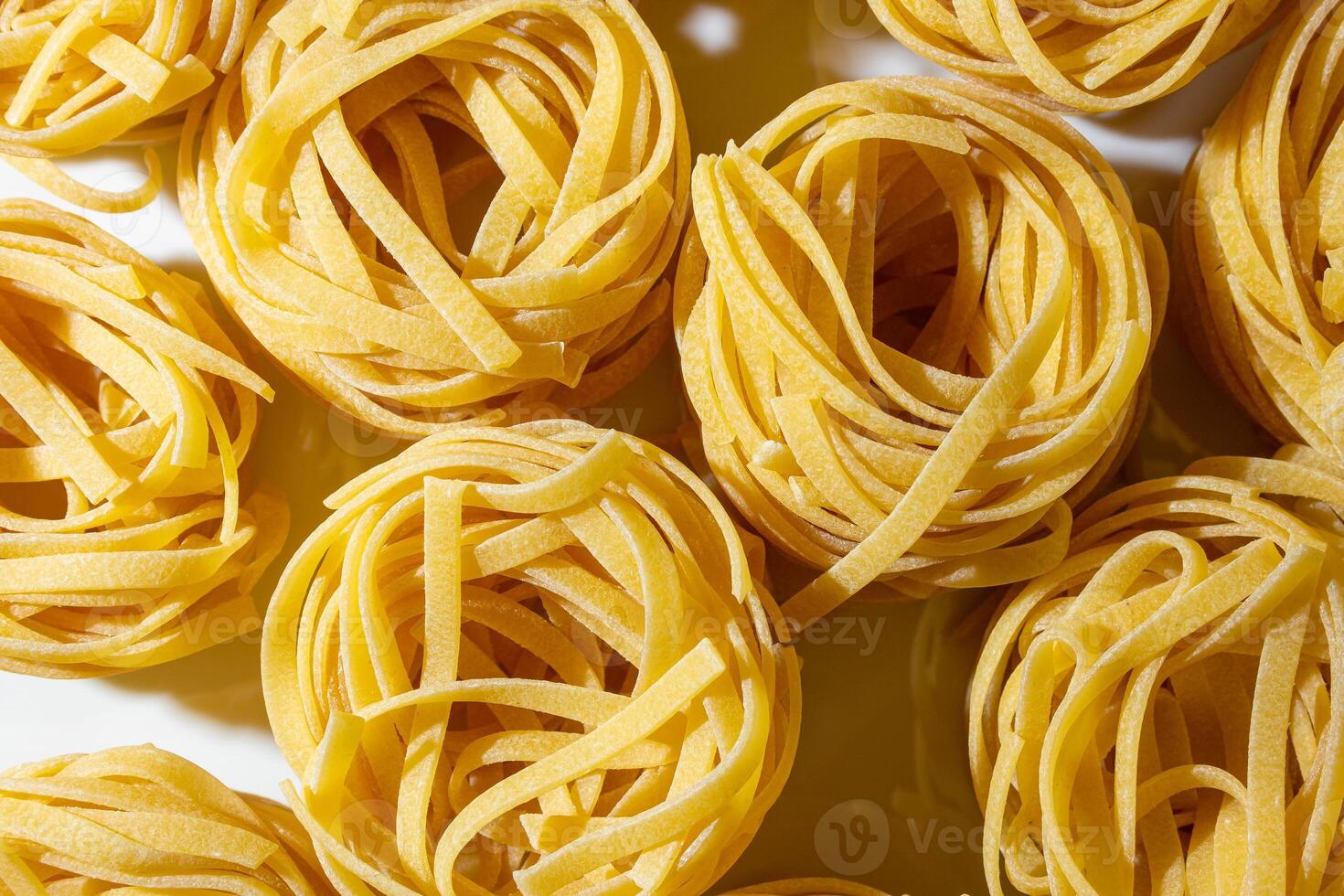 Uncooked Egg-Based Fettuccine Pasta. A Culinary Canvas of Ribbon-Shaped Macaroni, Creating a Lively and Textured Background for Gourmet Cooking. Dry Pasta. Raw Macaroni - Top View, Flat Lay photo