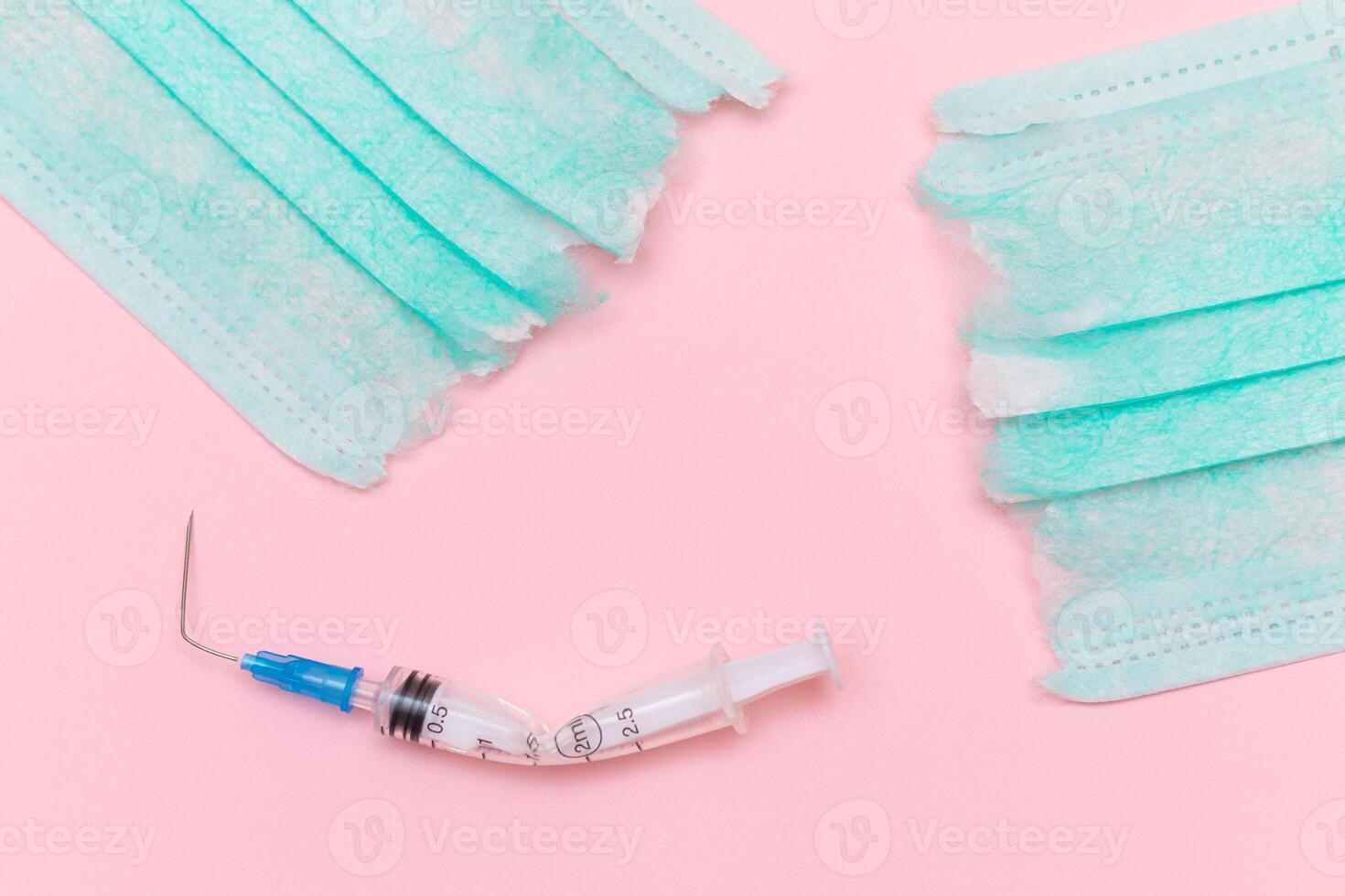 Anti Vaccine Movement and Anti Mask Concept - Broken Medical Syringe and Green Torn Medical Face Mask on the Pink Background. Pandemic and Lockdown End - Top View, Flat Lay photo