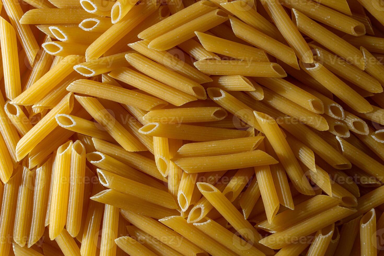 Uncooked Penne Rigate Pasta. A Culinary Canvas of Penne Macaroni, Creating a Lively and Textured Background for Gourmet Cooking. Dry Pasta. Raw Macaroni - Top View, Flat Lay photo