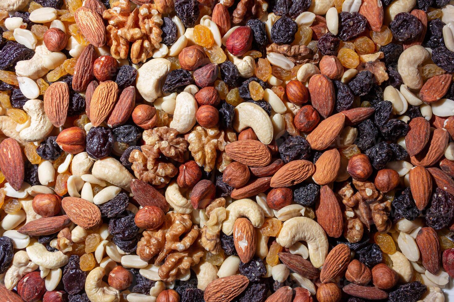Mixed Nuts. Almonds, Walnuts, Cashews, Peanuts, Hazelnuts, Dried Prunes and Raisins. Different Nut Mix. Background from Various Nuts and Dried Fruits photo