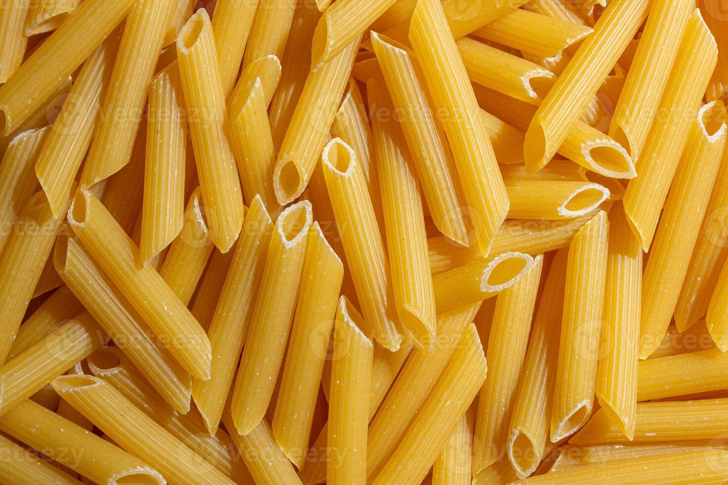 Uncooked Penne Rigate Pasta. A Culinary Canvas of Penne Macaroni, Creating a Lively and Textured Background for Gourmet Cooking. Dry Pasta. Raw Macaroni - Top View, Flat Lay photo