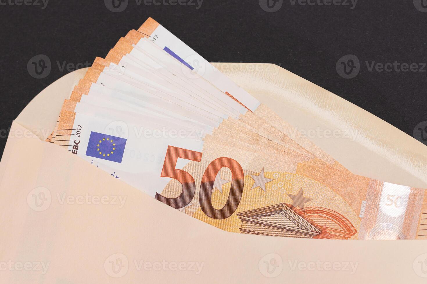 An Orange Paper Envelope with Stack of 50-Euro Banknotes Inside. Salary in Cash. Tax-Free System. Euro Currency. Payments with No Taxes. Orange Paper Money. A Lot of Fifty-Euro Bills photo