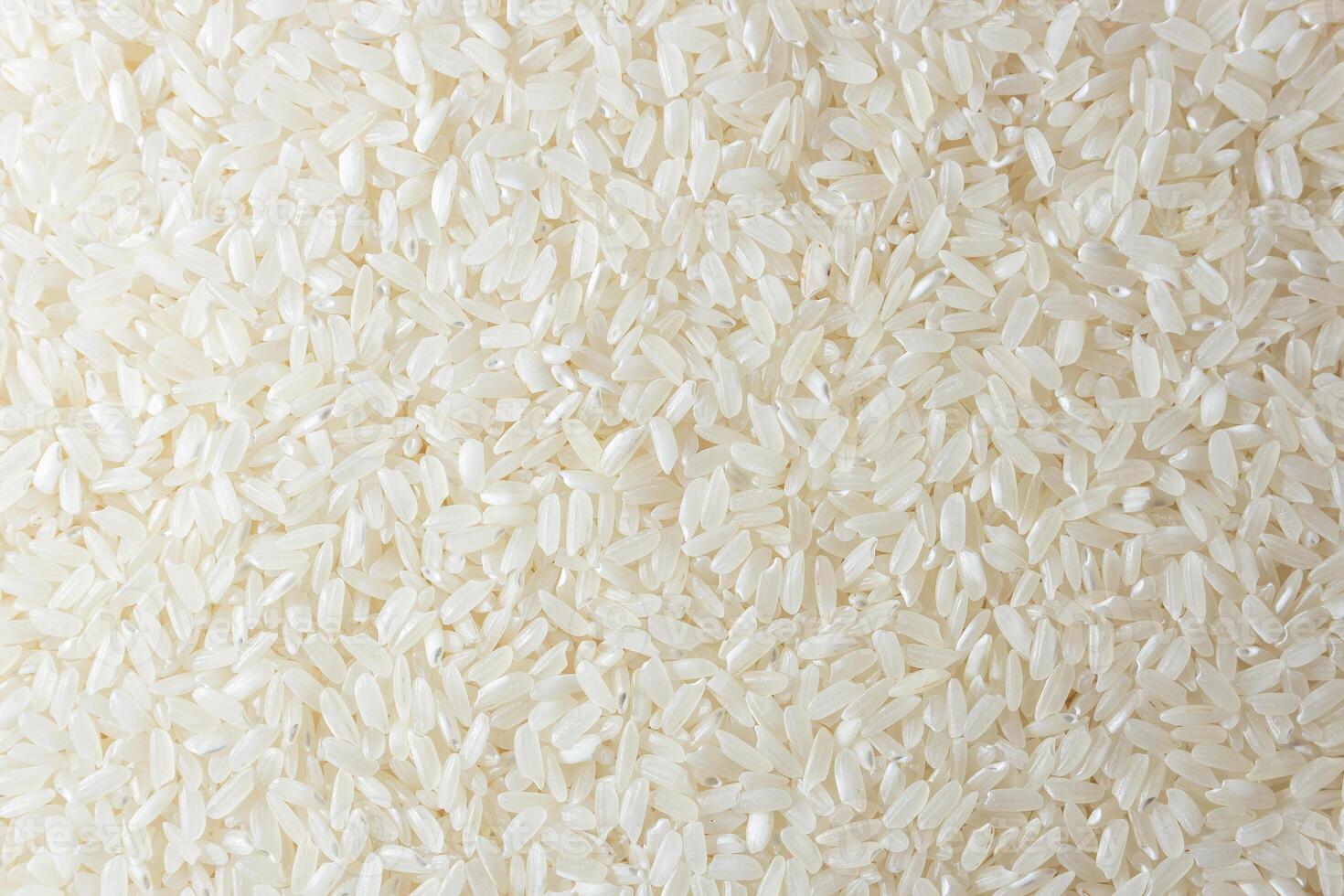 Dry Uncooked White Rice Background - Top View, Flat Lay. Scattered Raw Long Grain Rice. Asian Cuisine and Culture. Healthy Eating Ingredients. Diet Food photo