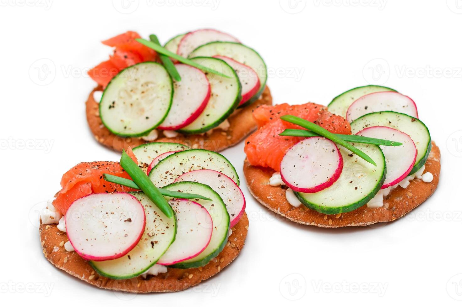 Crispy Cracker Sandwiches with Salmon, Cucumber, Radish, Cottage Cheese and Green Onions - Isolated on White. Easy Breakfast. Quick and Healthy Sandwiches. Crispbread with Tasty Filling - Isolation photo