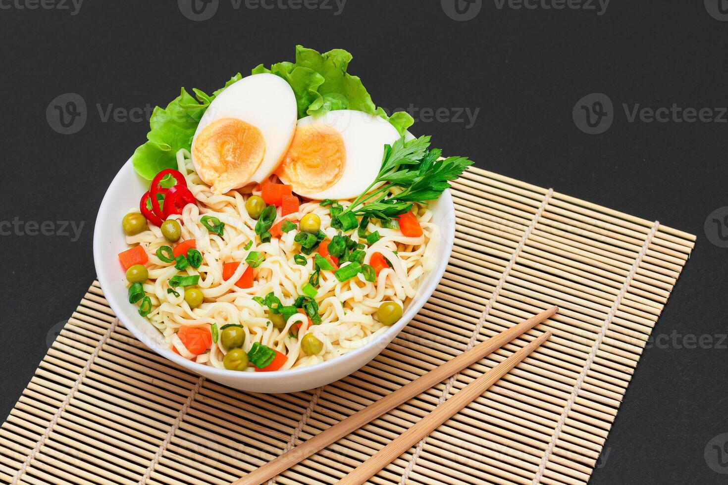 Beautiful Noodle Dish with Green Pea, Carrot, Eggs, Red Hot Pepper and Greens on Sushi Mat. Instant Noodles with Vegetables photo