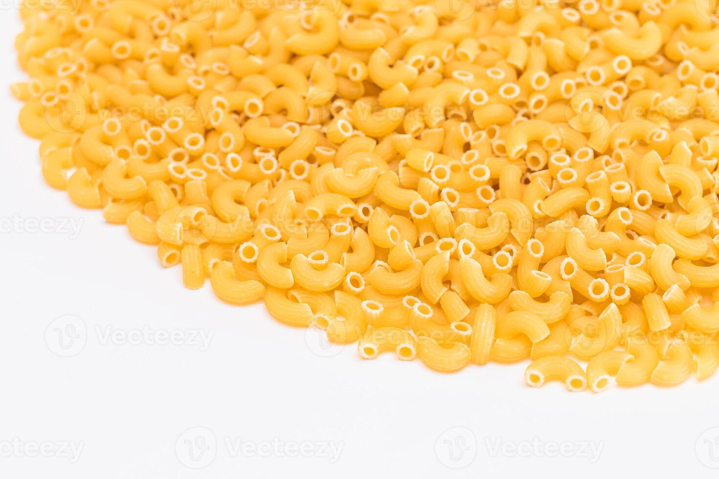 A Heap of Uncooked Chifferi Rigati Pasta on White Background. Fat and Unhealthy Food. Classic Dry Macaroni Texture. Italian Culture and Cuisine. Raw Pasta photo