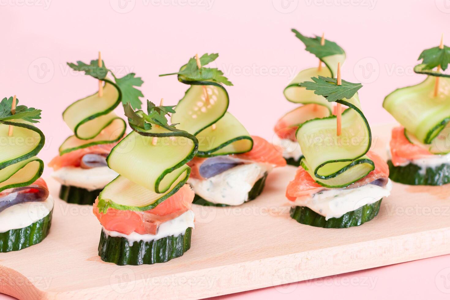 Canapes without Bread with Fresh Salmon, Cucumber and Cream Cheese on Wooden Cutting Board. Easy Breakfast. Diet Food. Quick and Healthy Sandwiches. Healthy Snacks with Tasty Fillings photo