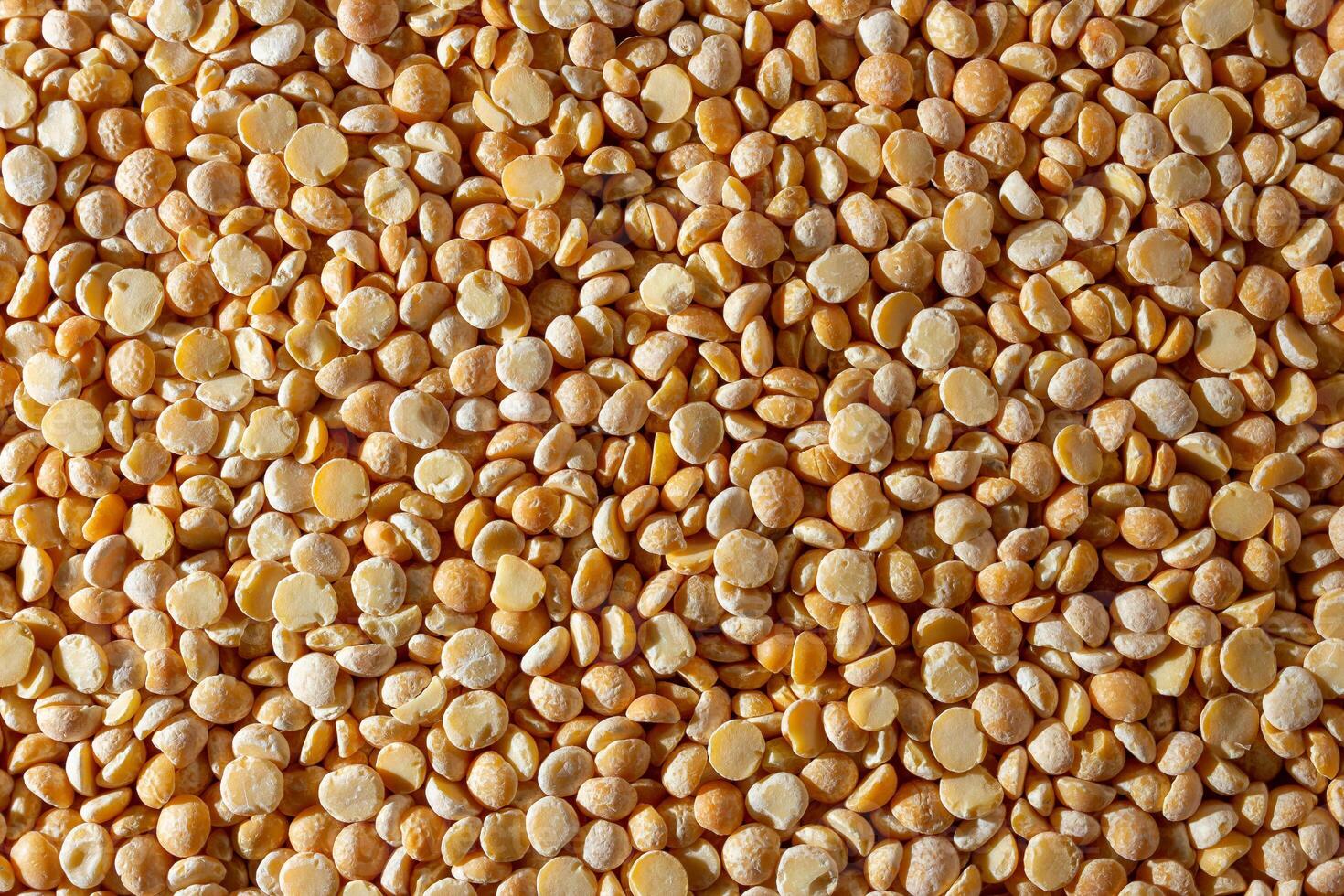 Uncooked Polished Split Peas Background. A Culinary Canvas of Dry Yellow Peas, Creating a Lively and Textured Background for Gourmet Cooking. Scattered Raw Polished Peas. Healthy Eating Ingredients photo