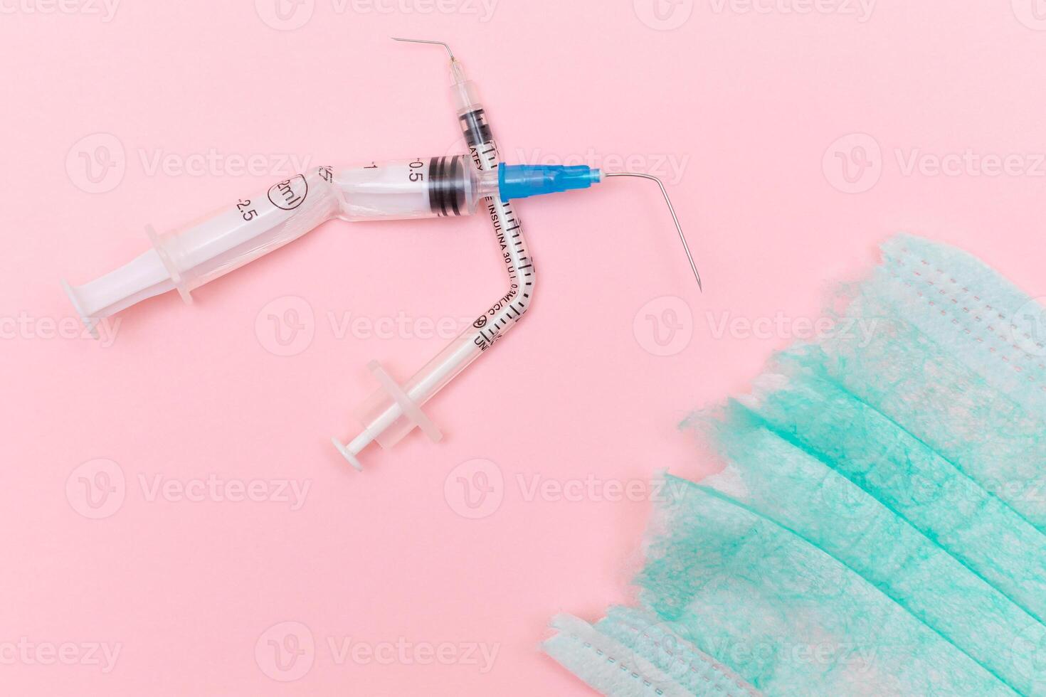 Anti Vaccine Movement and Anti Mask Concept - Broken Medical Syringe and Green Torn Medical Face Mask on the Pink Background. Pandemic and Lockdown End - Top View, Flat Lay photo