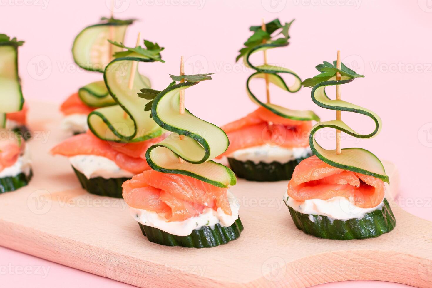 Canapes without Bread with Fresh Salmon, Cucumber and Cream Cheese on Wooden Cutting Board. Easy Breakfast. Diet Food. Quick and Healthy Sandwiches. Healthy Snacks with Tasty Fillings photo
