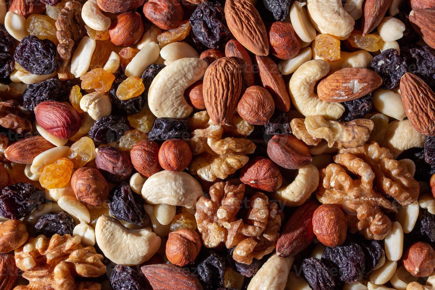 Mixed Nuts. Almonds, Walnuts, Cashews, Peanuts, Hazelnuts, Dried Prunes and Raisins. Different Nut Mix. Background from Various Nuts and Dried Fruits photo