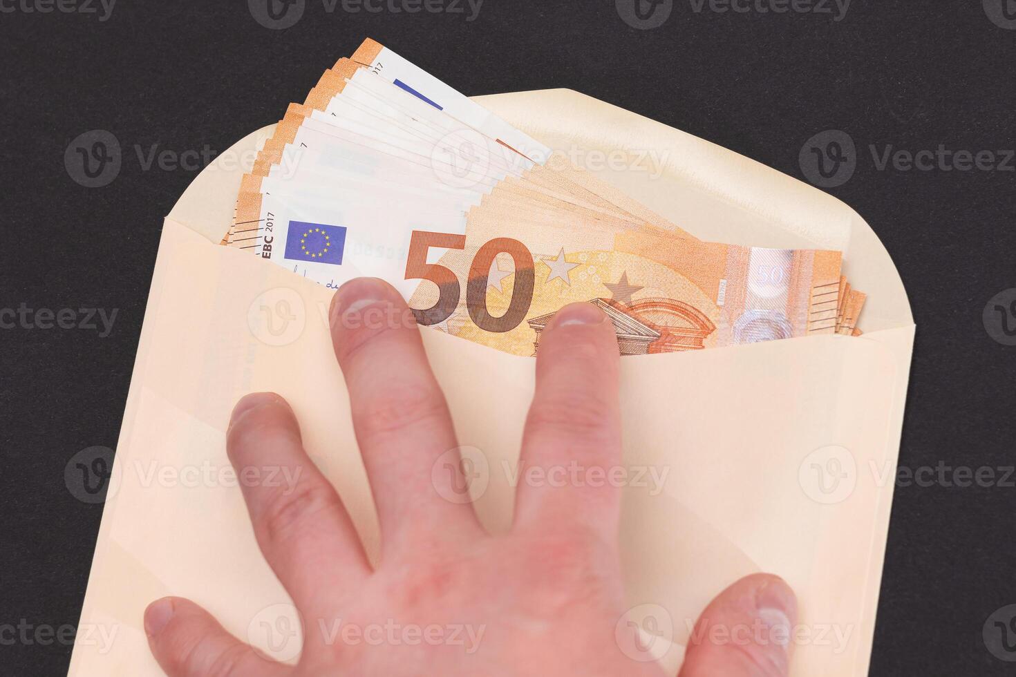Hand Holds An Orange Paper Envelope with Stack of 50-Euro Banknotes Inside. Salary in Cash. Tax-Free System. Euro Currency. Payments with No Taxes. Orange Paper Money. A Lot of Fifty-Euro Bills photo