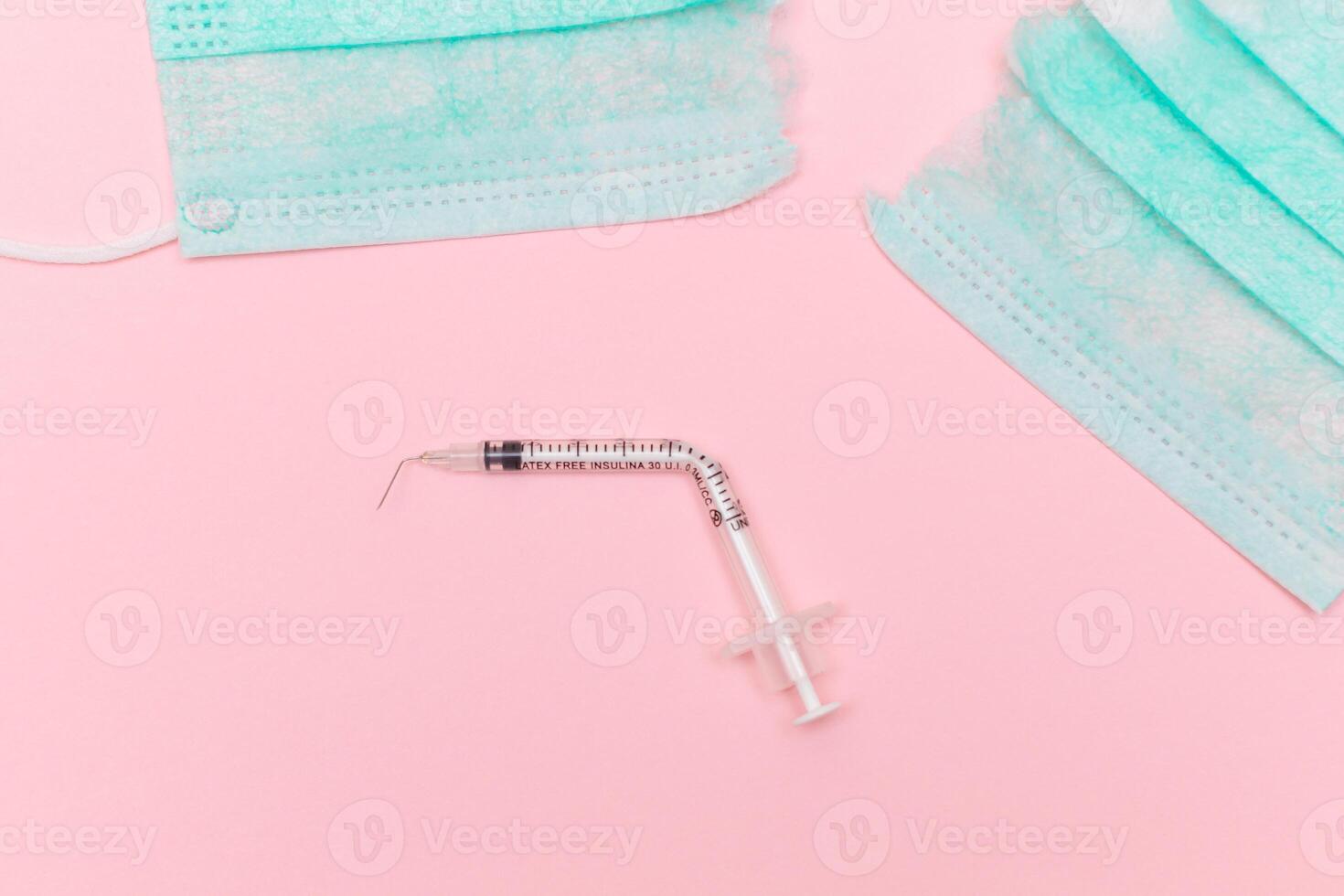 Anti Vaccine Movement and Anti Mask Concept - Broken Medical Syringe and Green Torn Medical Face Mask on the Pink Background. Pandemic and Lockdown End - Top View, Flat Lay photo