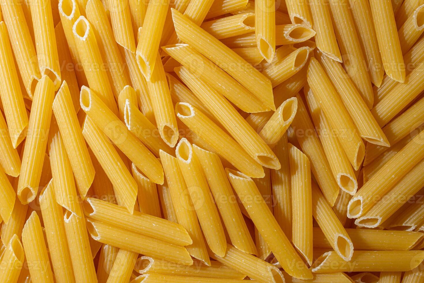 Uncooked Penne Rigate Pasta. A Culinary Canvas of Penne Macaroni, Creating a Lively and Textured Background for Gourmet Cooking. Dry Pasta. Raw Macaroni - Top View, Flat Lay photo