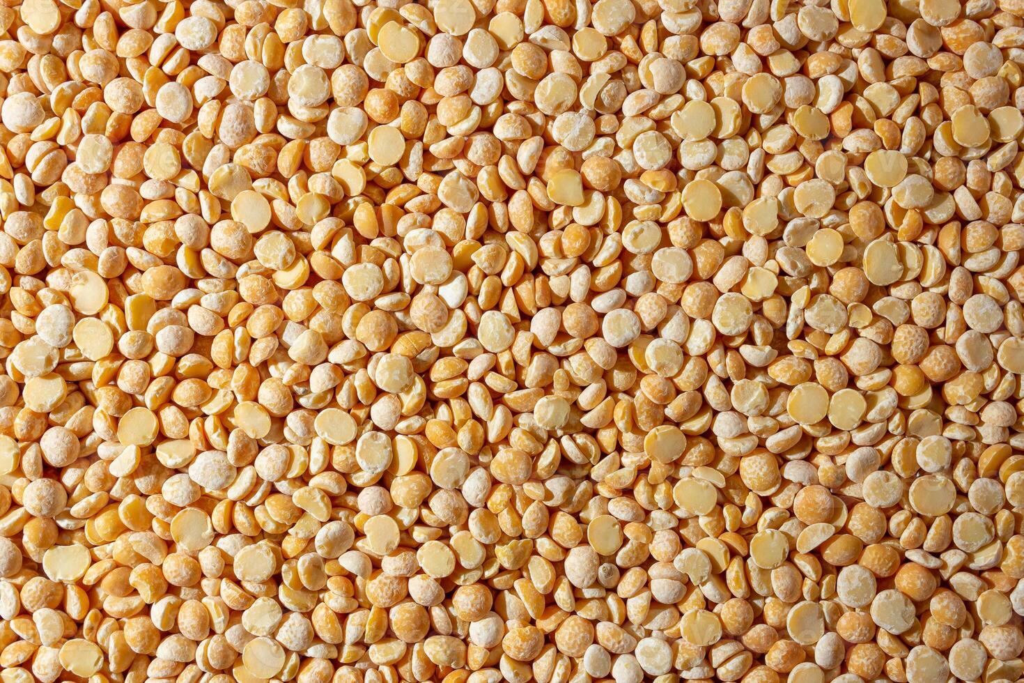 Uncooked Polished Split Peas Background. A Culinary Canvas of Dry Yellow Peas, Creating a Lively and Textured Background for Gourmet Cooking. Scattered Raw Polished Peas. Healthy Eating Ingredients photo