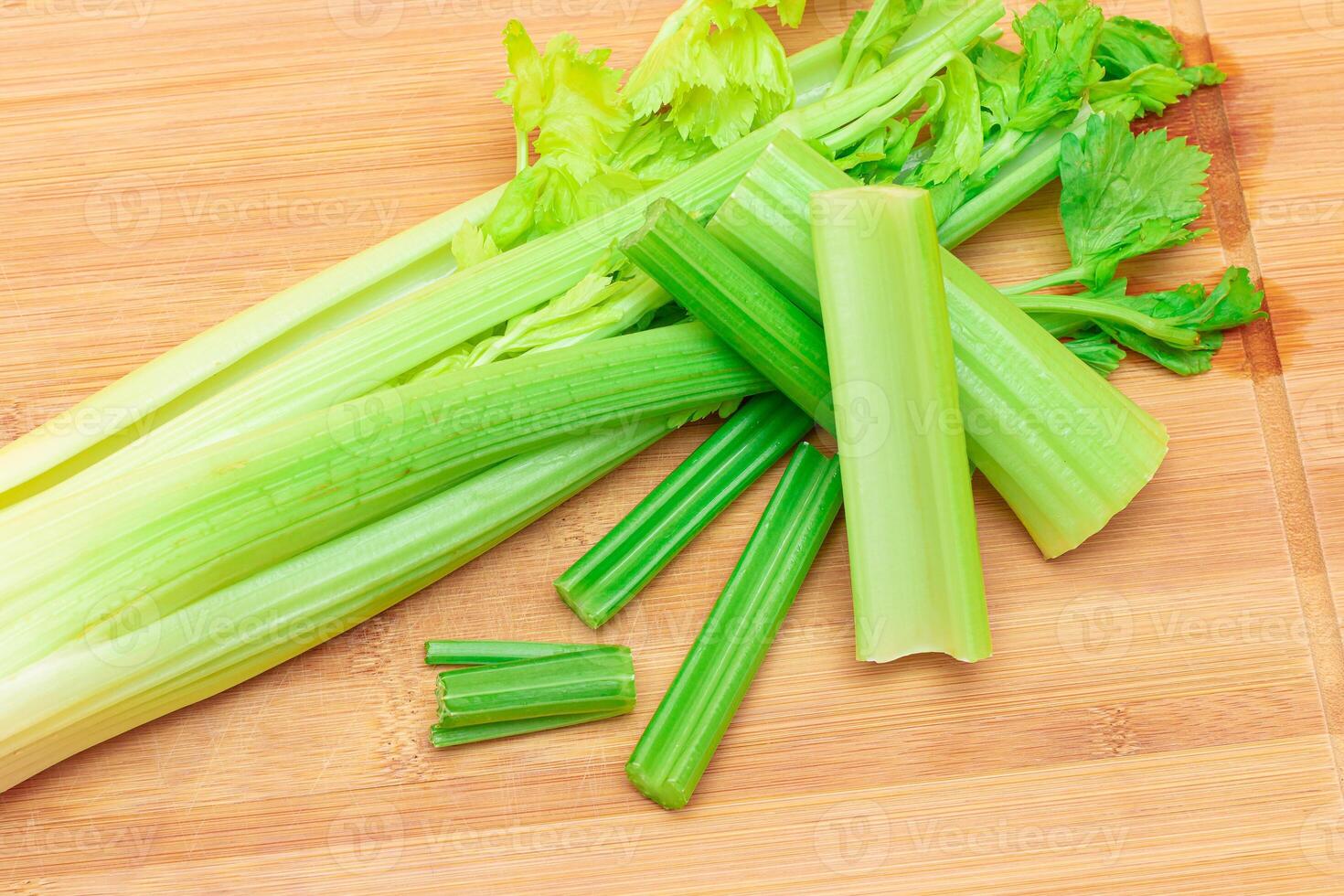 Fresh Celery Stem and Chopped Celery Sticks on Wooden Cutting Board. Vegan and Vegetarian Culture. Raw Food. Healthy Diet with Negative Calorie Content. Slimming Food photo