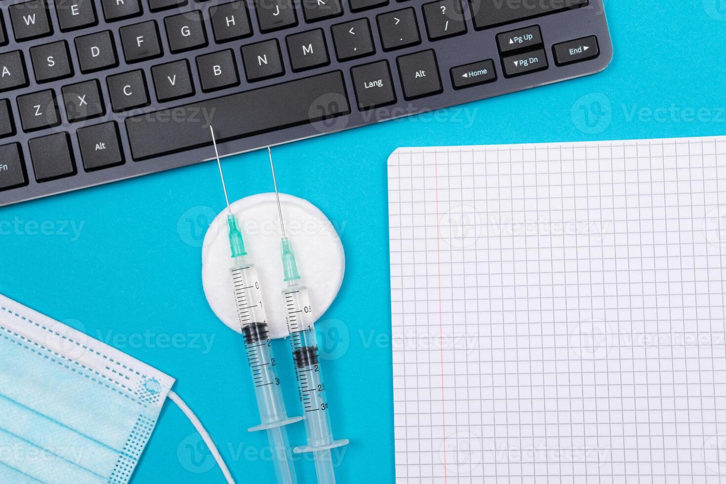 Vaccination, Immunology or Revaccination Concept - Two Medical Syringe Lying on Blue Table in Doctor's Office in a Hospital or Clinic. Opened Blank Notepad - Mock Up with Copy Space photo