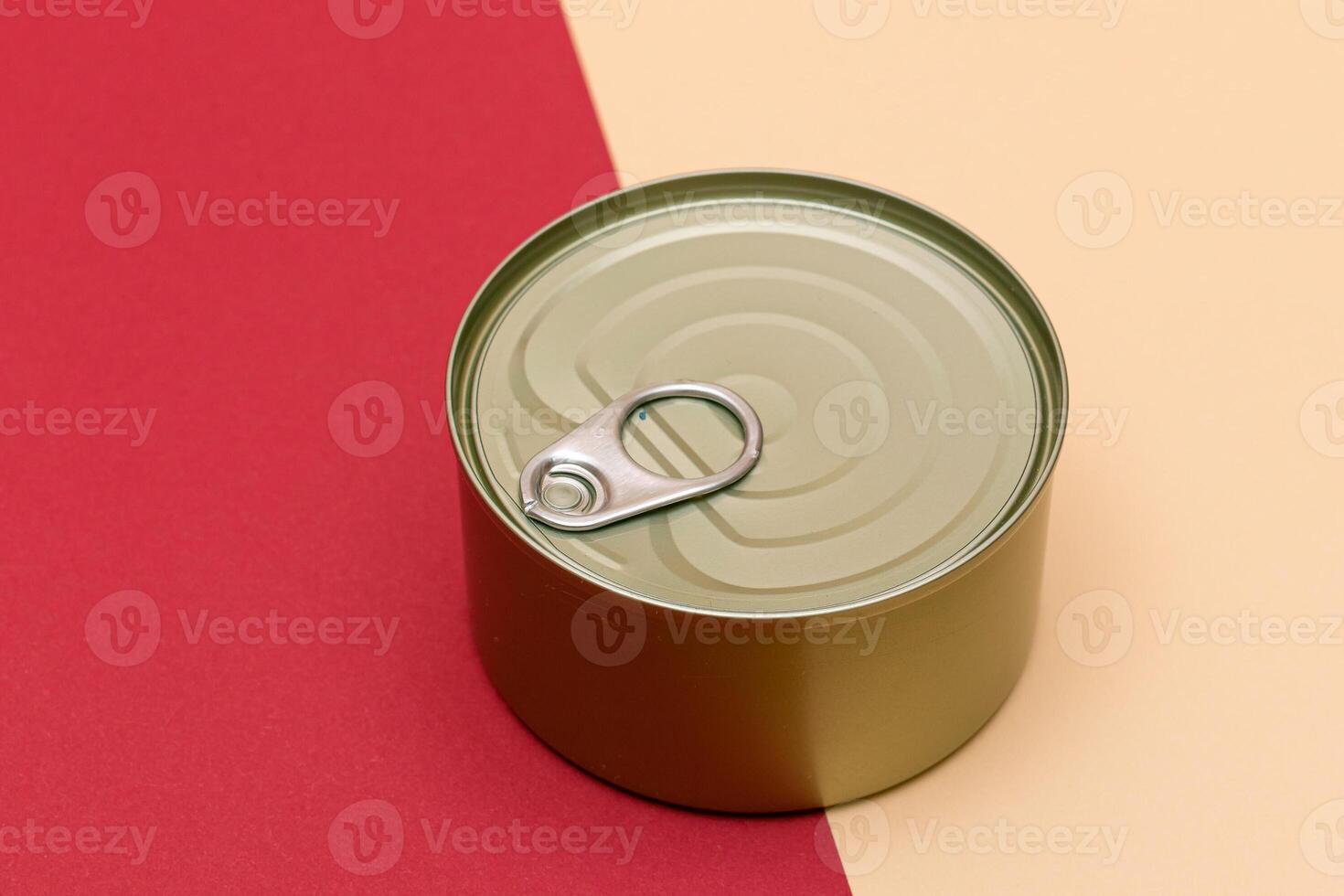 Unopened Tin Can with Blank Edge on Split Red and Beige Background. Canned Food. Aluminum Can for Safe and Long Term Storage of Food. Steel Sealed Food Storage Container photo