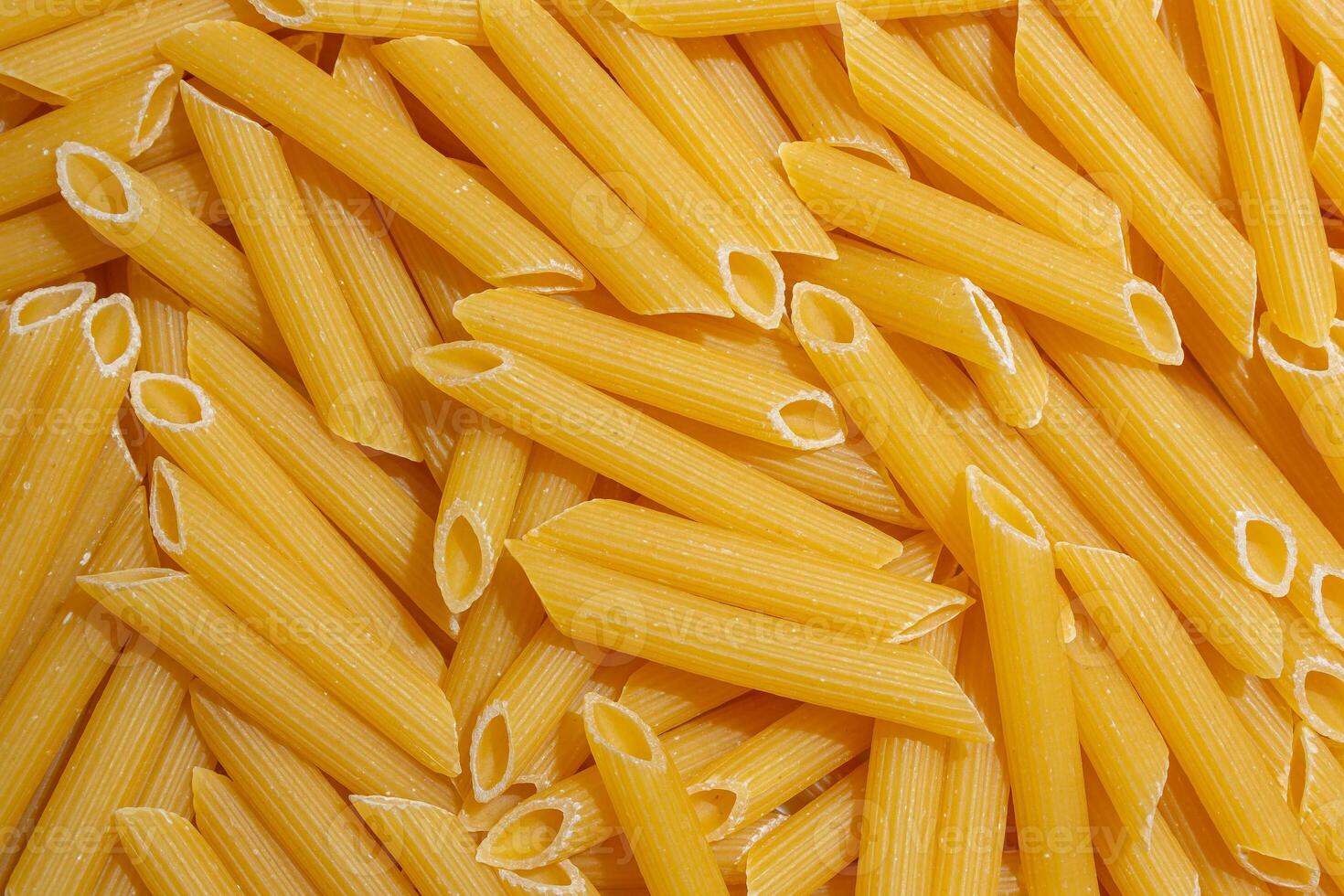 Uncooked Penne Rigate Pasta. A Culinary Canvas of Penne Macaroni, Creating a Lively and Textured Background for Gourmet Cooking. Dry Pasta. Raw Macaroni - Top View, Flat Lay photo