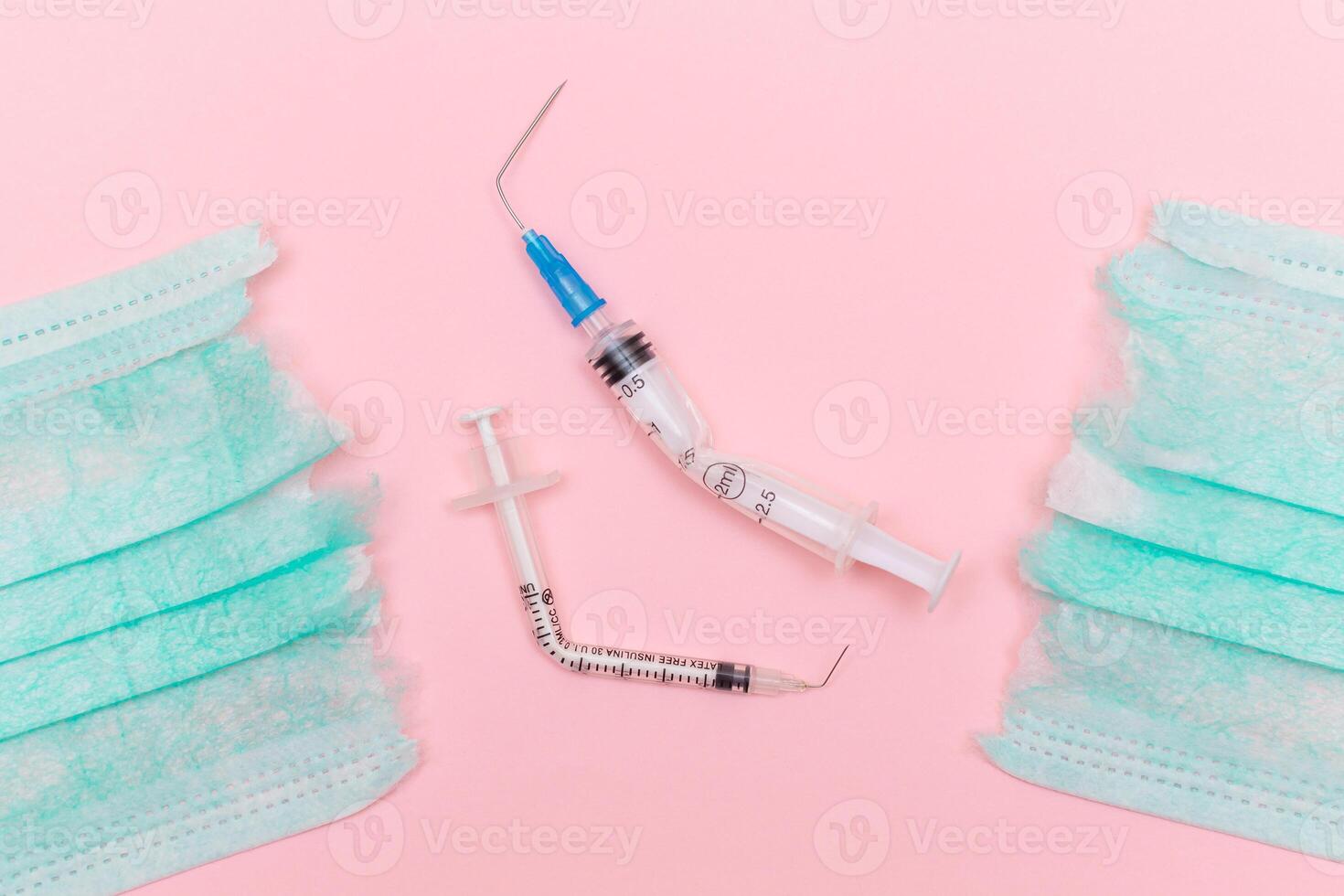 Anti Vaccine Movement and Anti Mask Concept - Broken Medical Syringe and Green Torn Medical Face Mask on the Pink Background. Pandemic and Lockdown End - Top View, Flat Lay photo