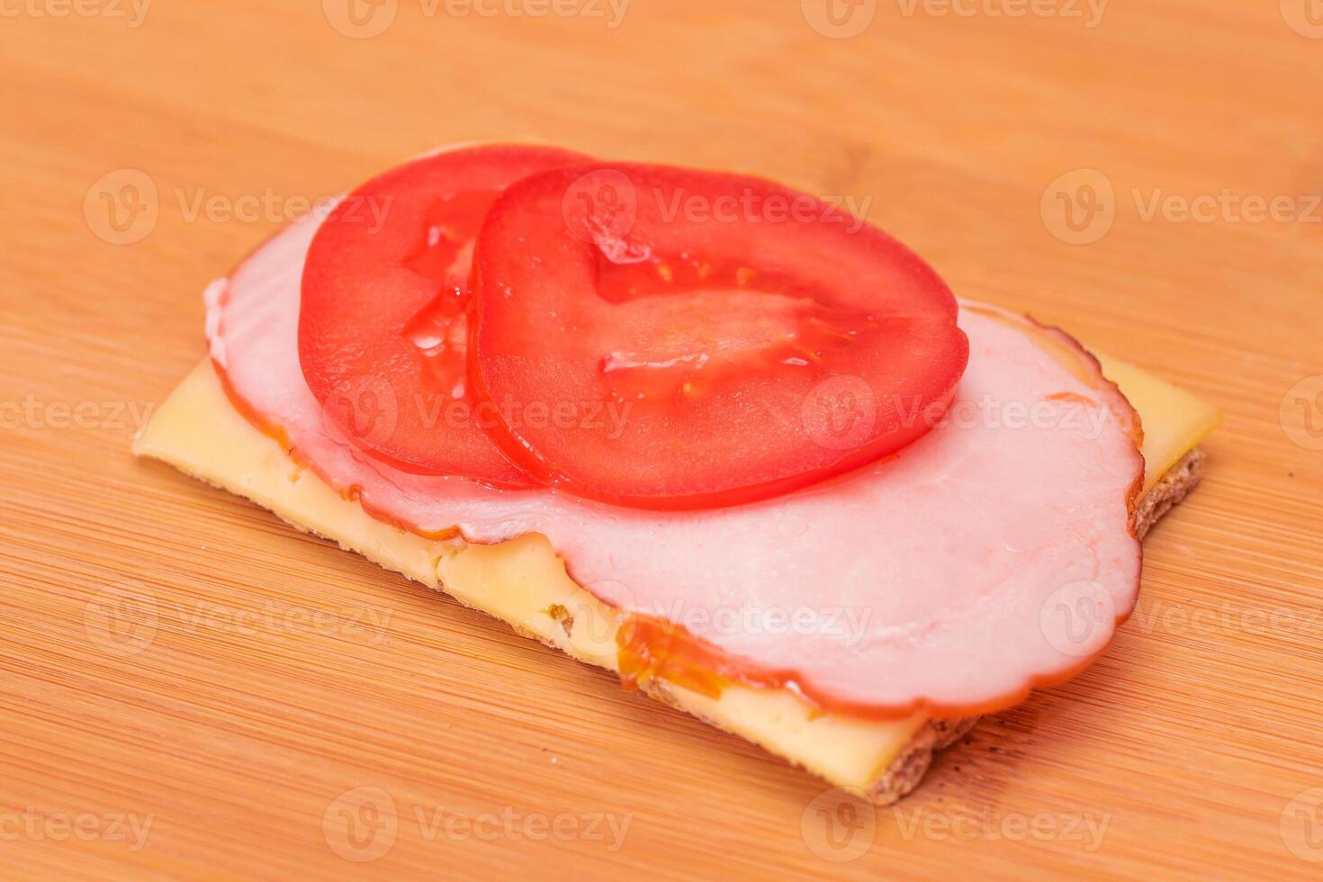 Whole Grain Crispbread with Tomato, Ham and Cheese on Bamboo Cutting Board. Easy Breakfast. Quick and Healthy Sandwiches. Crispbread with Tasty Filling. Healthy Dietary Snack photo