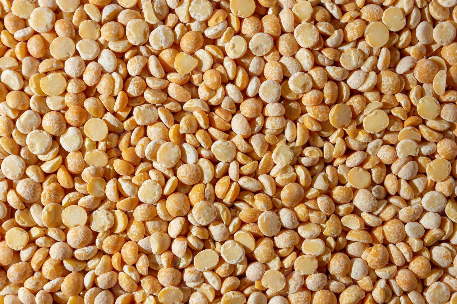 Uncooked Polished Split Peas Background. A Culinary Canvas of Dry Yellow Peas, Creating a Lively and Textured Background for Gourmet Cooking. Scattered Raw Polished Peas. Healthy Eating Ingredients photo