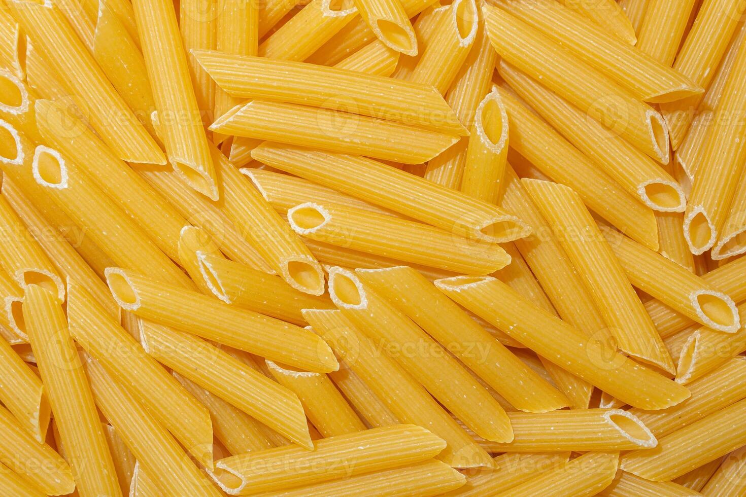 Uncooked Penne Rigate Pasta. A Culinary Canvas of Penne Macaroni, Creating a Lively and Textured Background for Gourmet Cooking. Dry Pasta. Raw Macaroni - Top View, Flat Lay photo