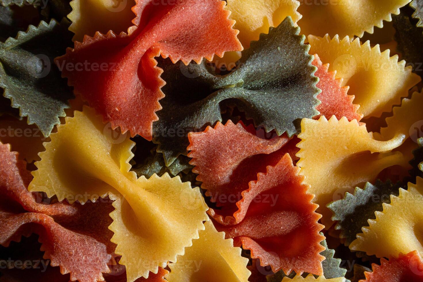 Uncooked Vibrant Colored Farfalle Pasta. A Culinary Canvas of Multicolored Bow-Tie Macaroni, Creating a Lively and Textured Background for Gourmet Cooking Enthusiasts. Colored Dry Pasta. Raw Macaroni photo