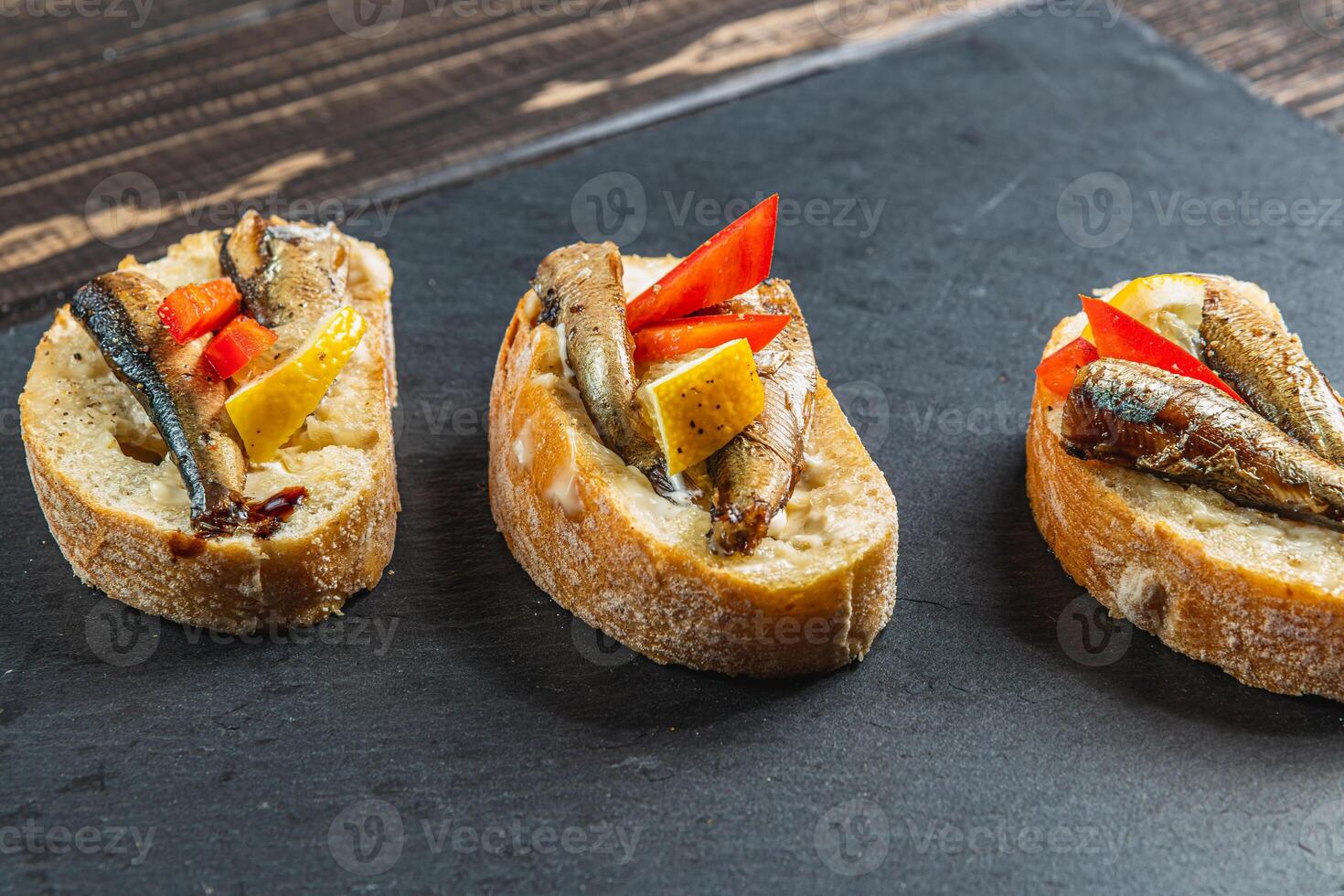 three fish sandwiches on a stone board on the table photo