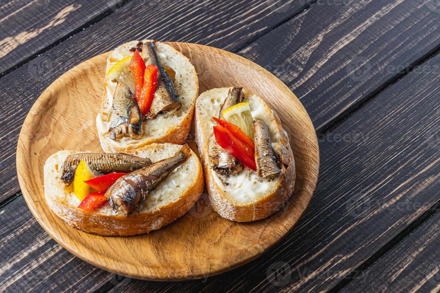fish sandwich with butter and sprats lemon and red pepper on a dark table photo