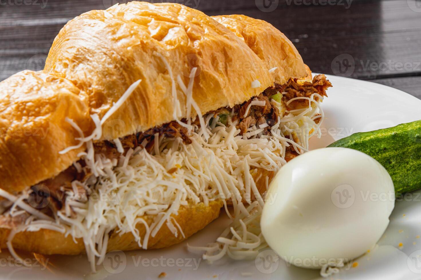 Croissant sandwich with tuna on a white plate on a dark table close up side view photo